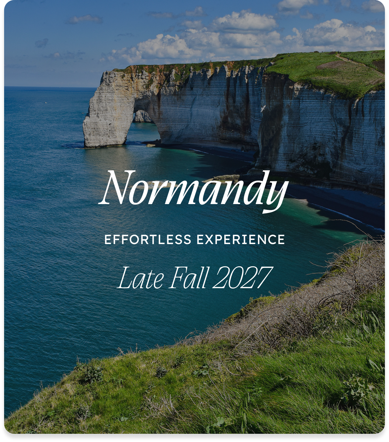 Photograph of white chalk cliffs with green grass on top, overlooking the Atlantic Ocean in Normandy, France, under a partly cloudy sky, with text overlay describing a travel experience in late fall 2027.
