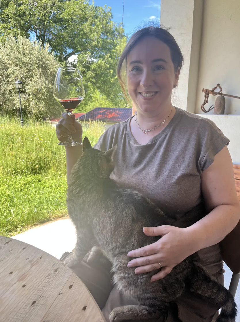 A women holds a glass of wine and a cat outside on a terrace while on a trip in France with travel company Maison d'Amies.
