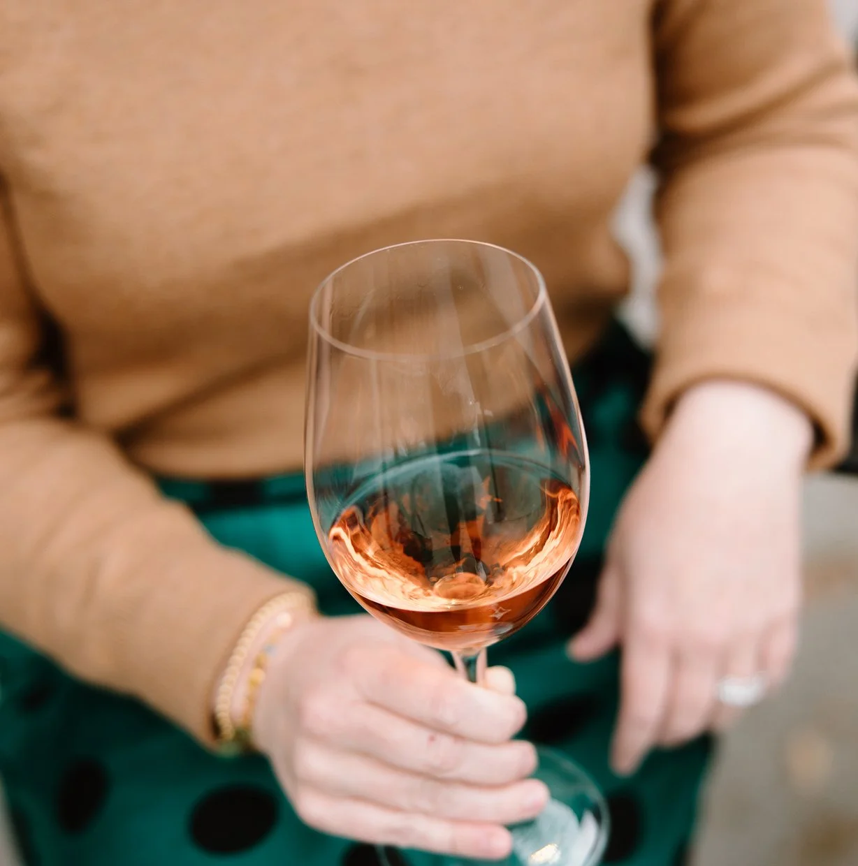 Person holding a glass of pink rosé wine.