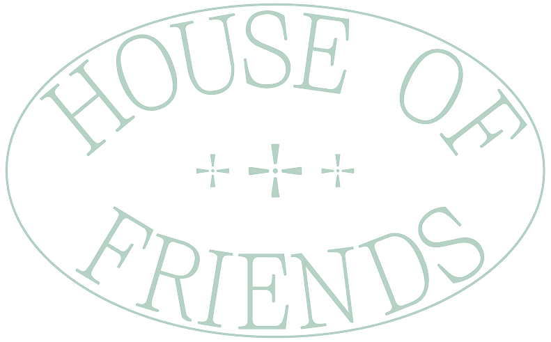 The image shows a white oval-shaped sign with the text "HOUSE OF FRIENDS" in large, uppercase letters. There are three plus signs in the middle of the sign, evenly spaced.