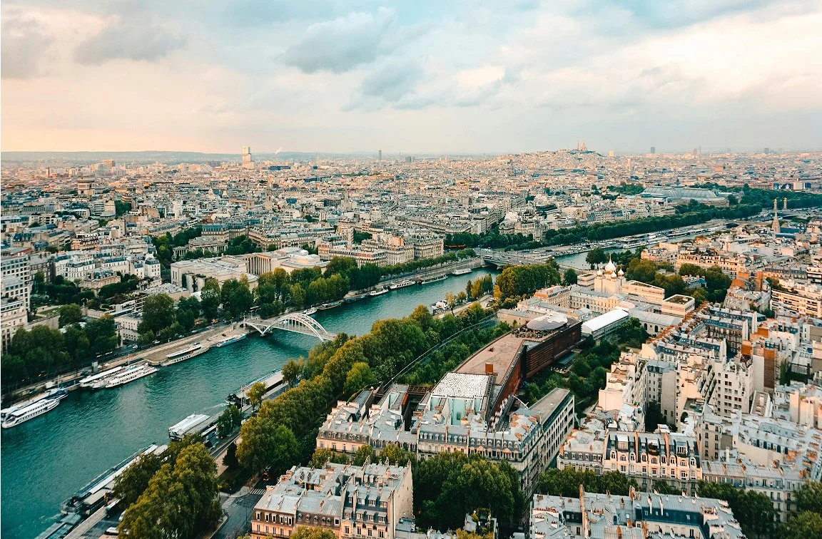 Aerial view of Paris showing the Seine River, city buildings, and cloudy sky