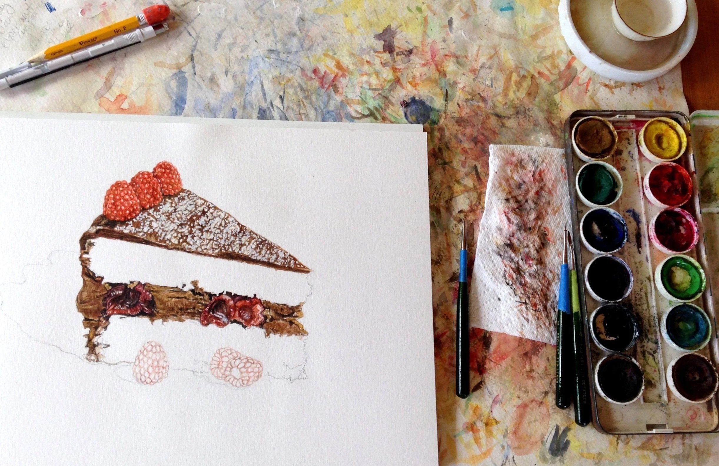 Work in progress photo of creating "The Starving Artist Cookbook" by Sara Zin showing a watercolor painting of a slice of cake topped with raspberries.