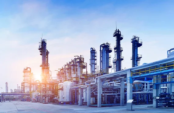 Industrial refinery with multiple tall pipes and structures at sunset