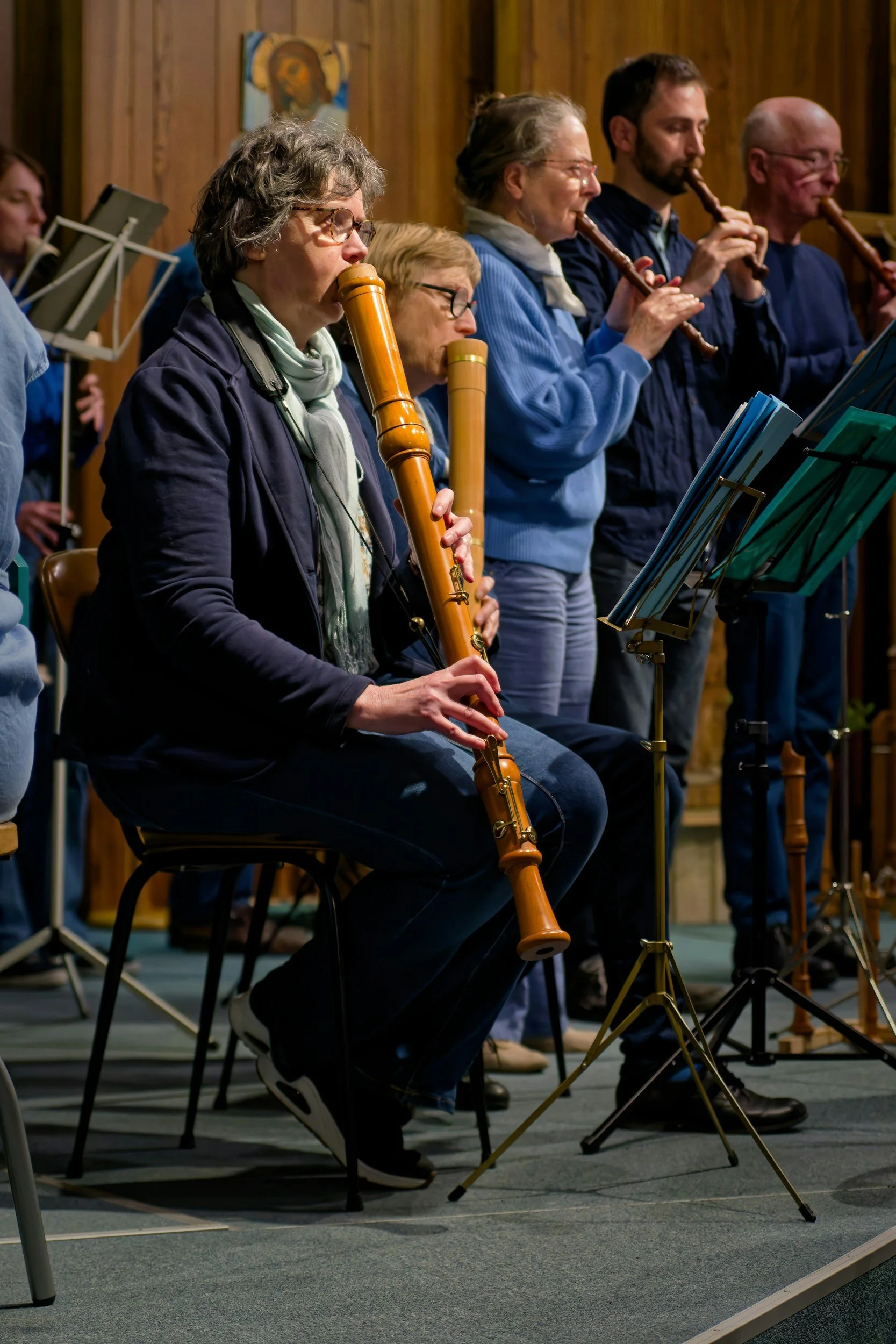 Group of people playing recorders during a musical rehearsal in a church or community hall.