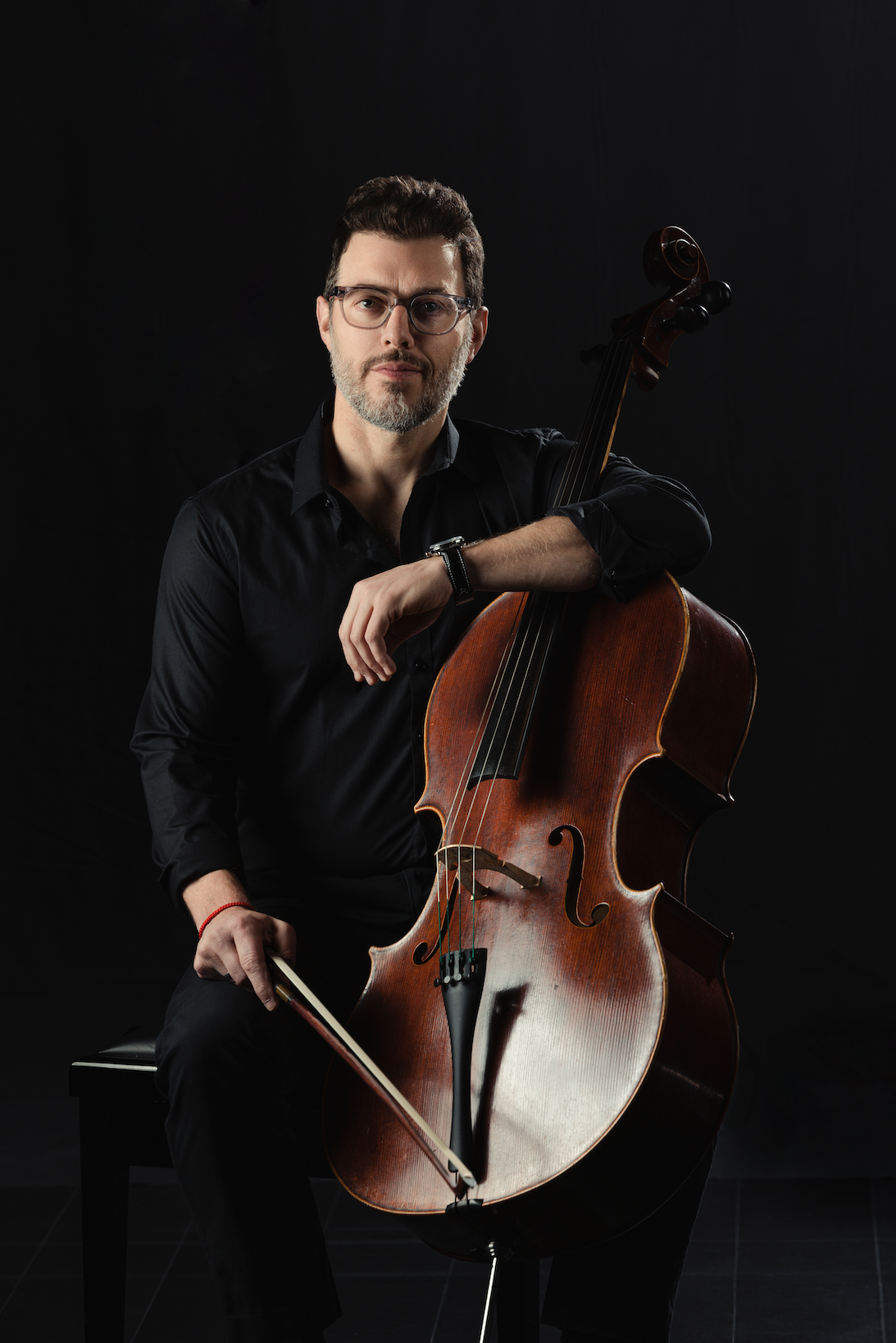 Nicholas Tzavaras holding a cello and a bow.