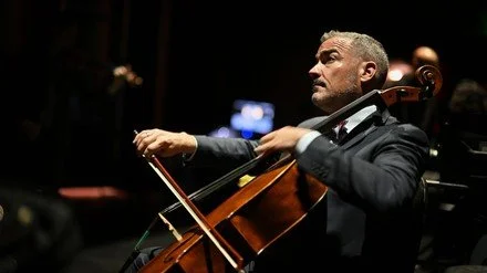 Joshua Gindele playing the cello in concert.