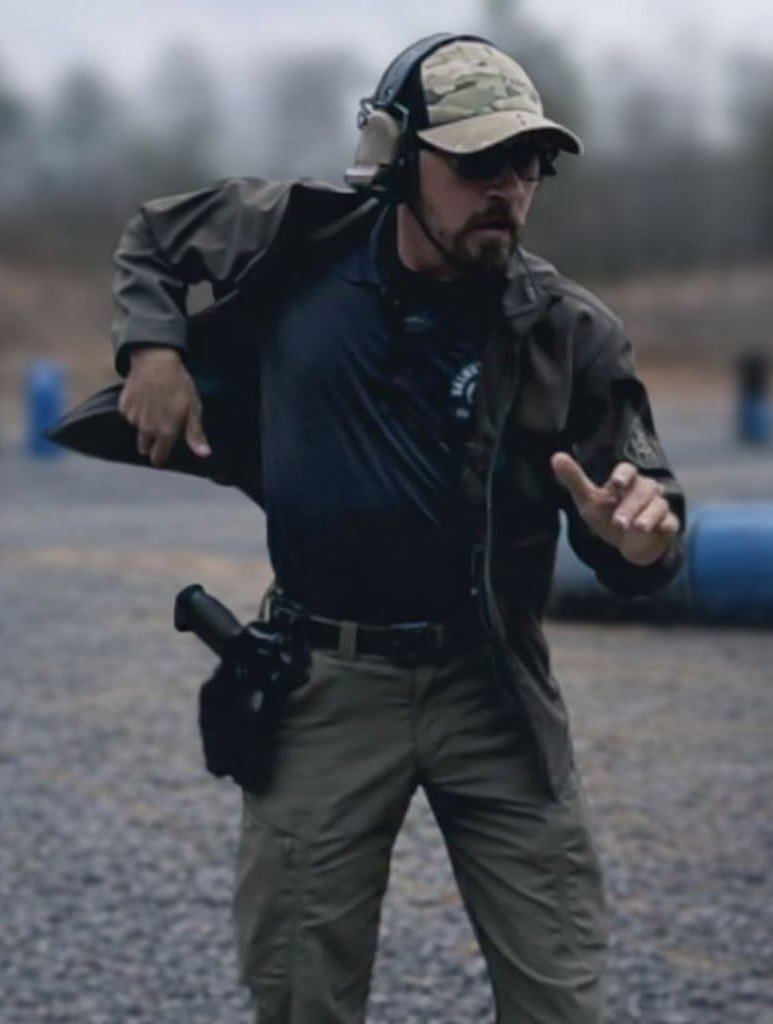Man dressed in tactical gear running outdoors with a headset and sunglasses