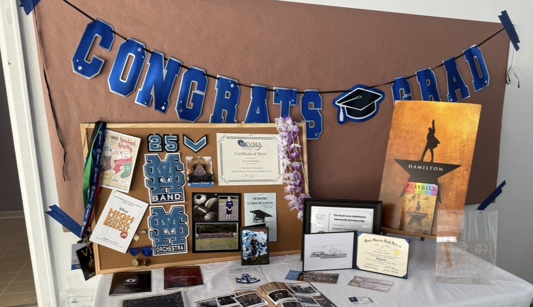 Display board with graduation decorations, a congratulatory banner, certificates, photos, medals, and graduation-themed posters.