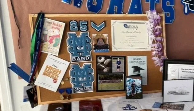 A bulletin board with school memorabilia, medals, a diploma, photos, and decorations, supporting Mississippi State University alumni.