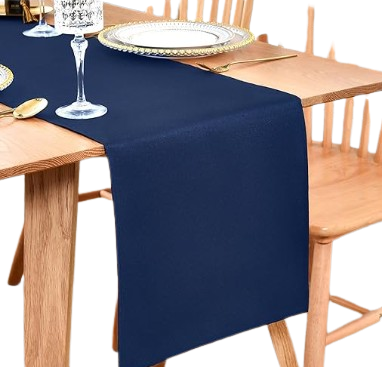 Dining table set with navy blue table runner, glassware, a plate, and gold utensils, surrounded by wooden chairs.