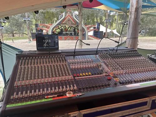 Large analogue mixing console overlooking an outdoor stage