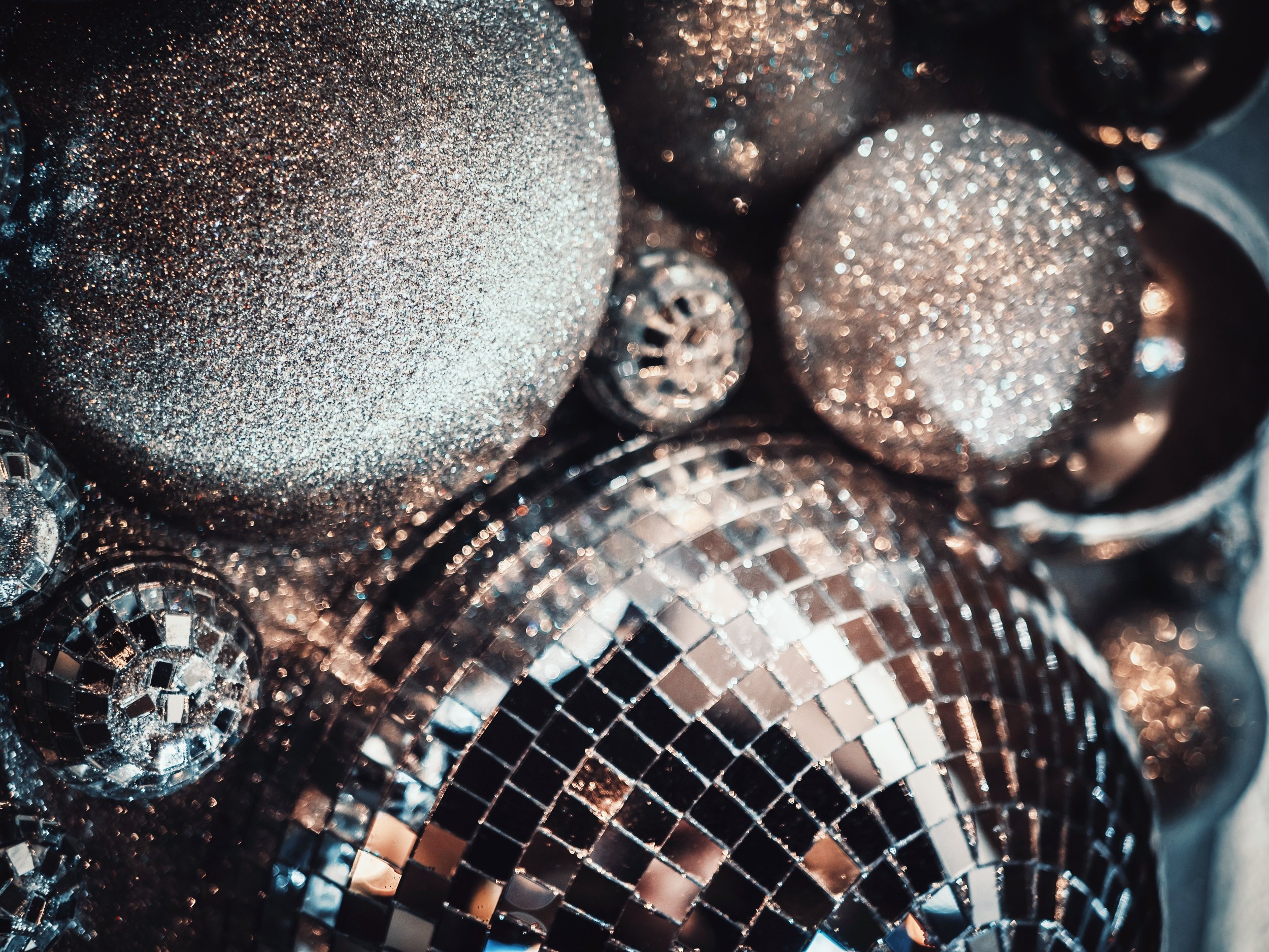 Close-up of a glittery, textured disco ball with a metallic surface reflecting light and creating a sparkling effect.