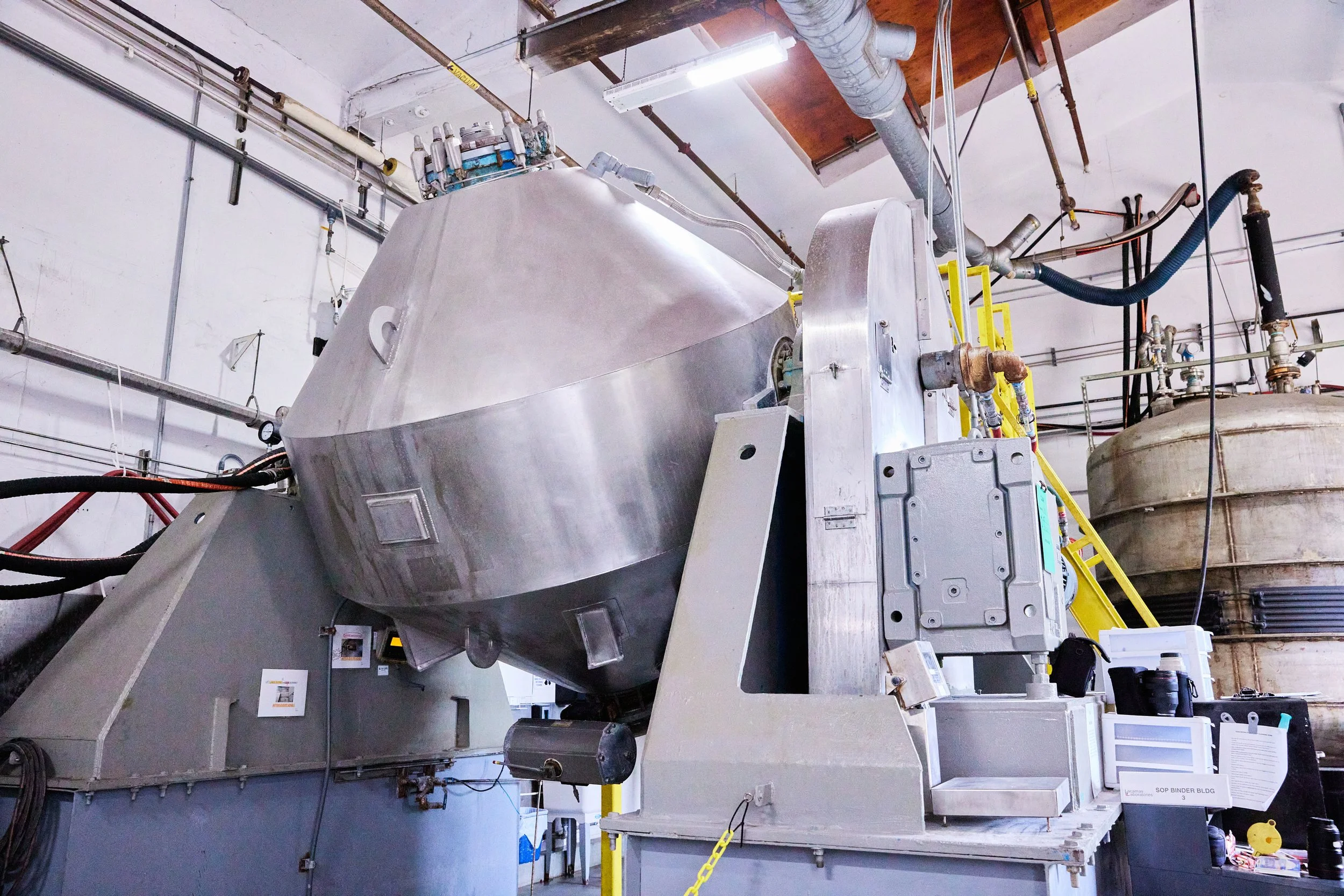 Industrial laboratory with stainless steel equipment, pipes, valves, and machinery used for scientific research or manufacturing processes.