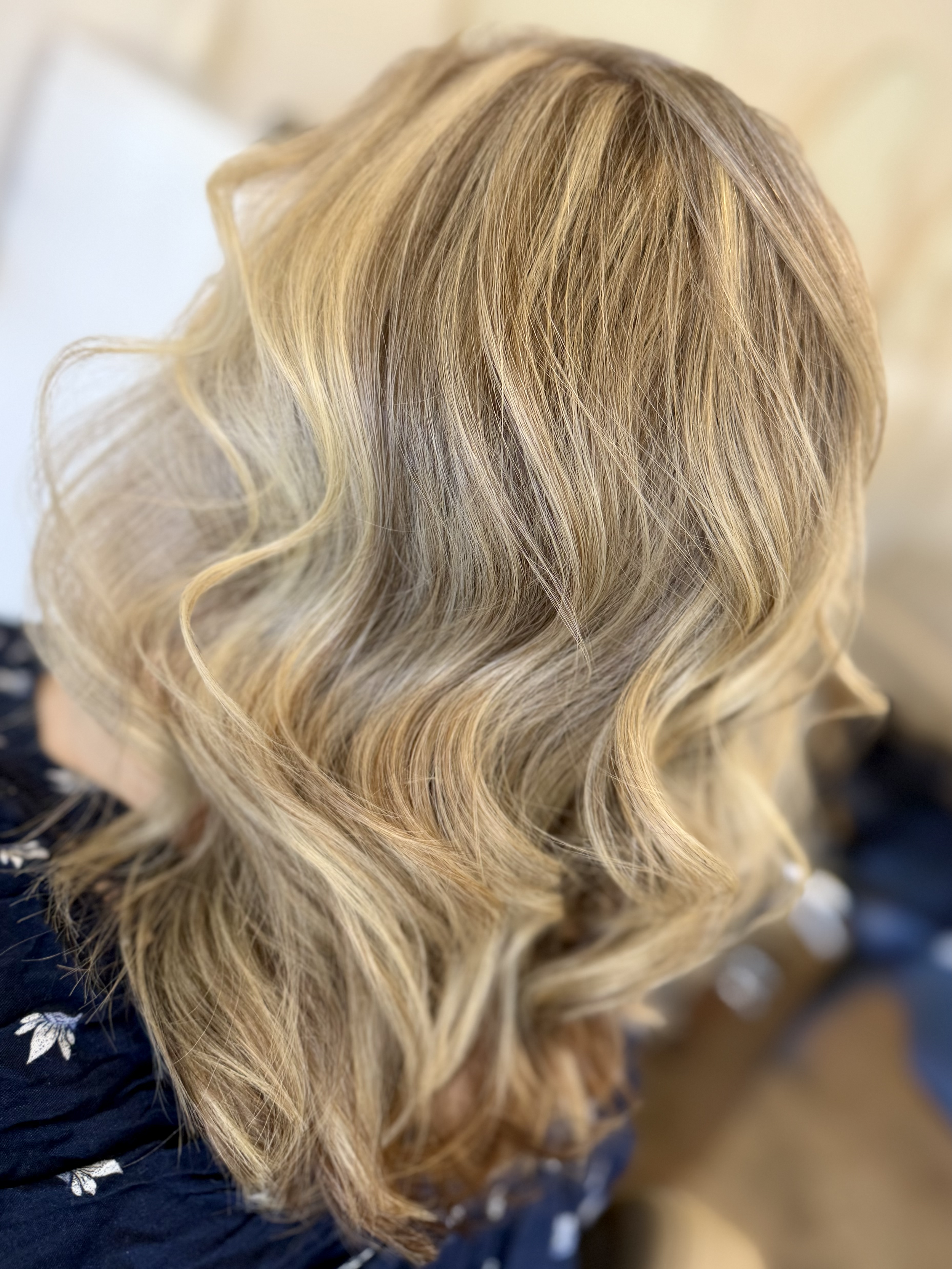 Close-up of a person's wavy, blonde hair styled with loose curls.