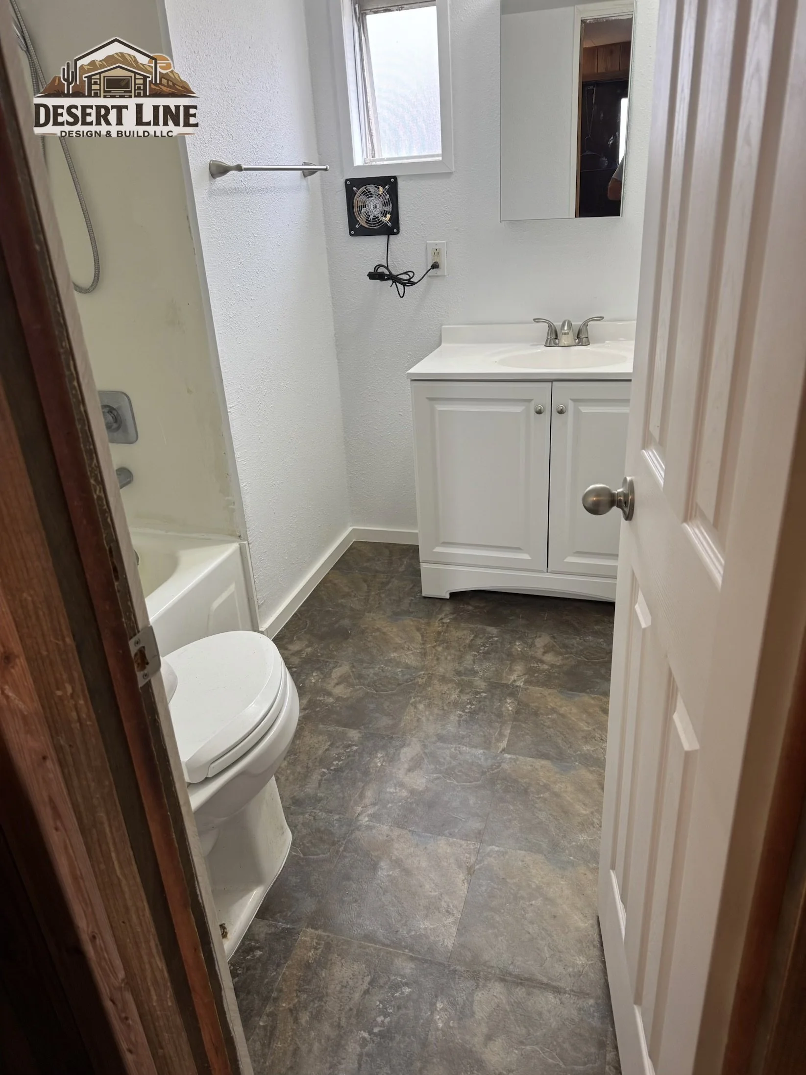 Small bathroom with white walls, a white vanity with sink, mirror, small window, vent, and toilet, with tiled floor.
