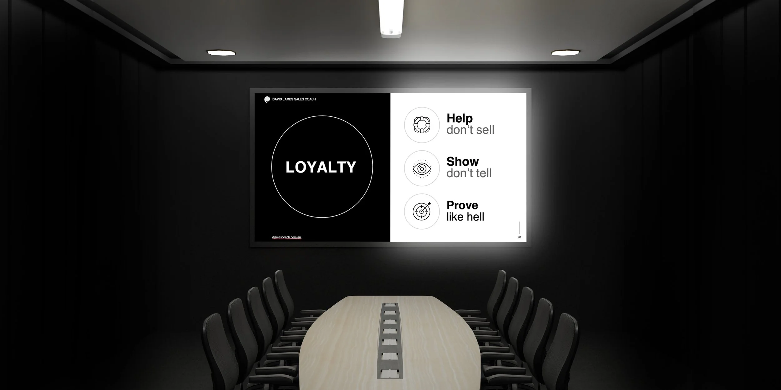 A conference room with a long table and black chairs. A large screen on the wall displays the word 'LOYALTY' inside a circle, with additional text and icons on the right side including 'Help don't sell,' 'Show don't tell,' and 'Prove like hell.'