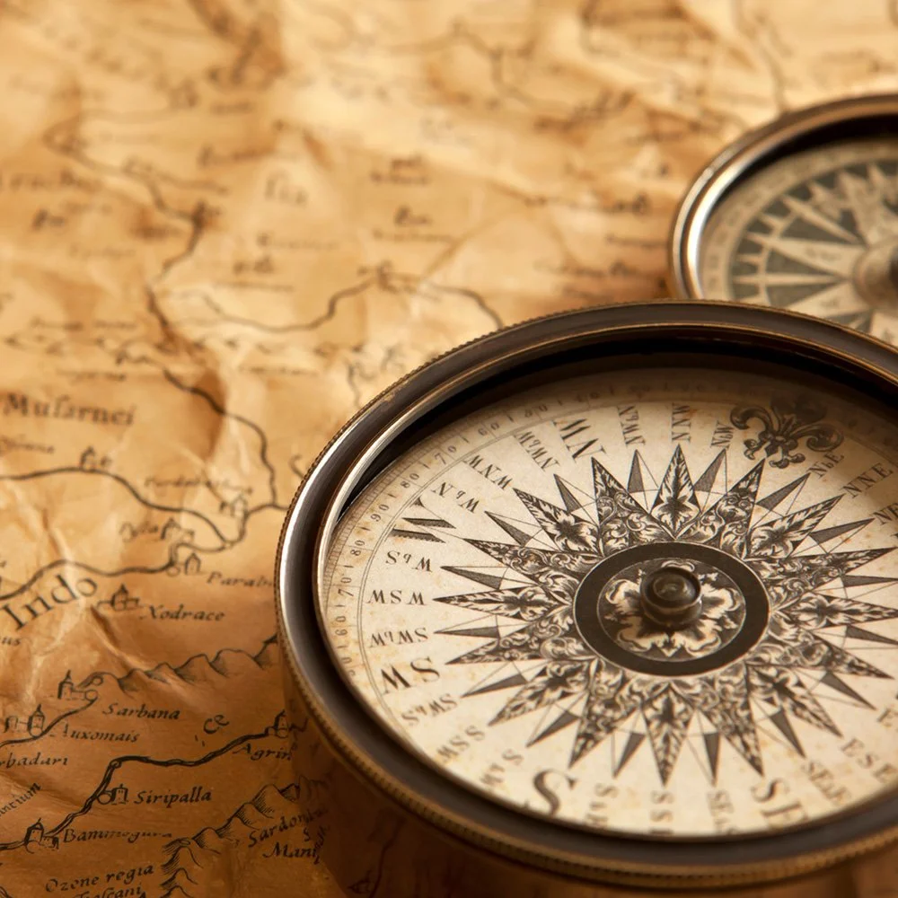 A vintage compass resting on an ancient, weathered map with detailed illustrations of regions and rivers.