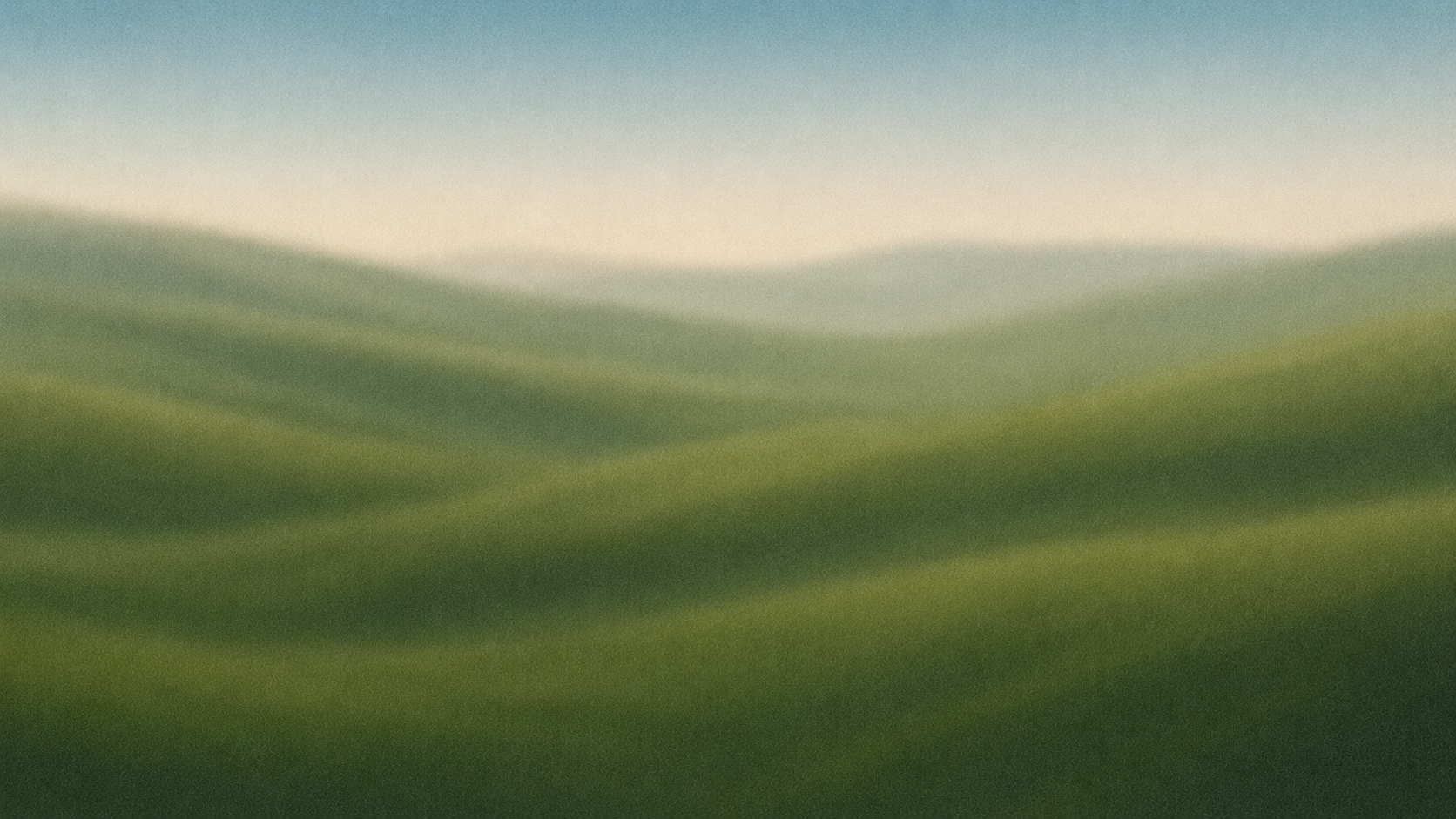 Blurred landscape image of green rolling hills with a pale sky.