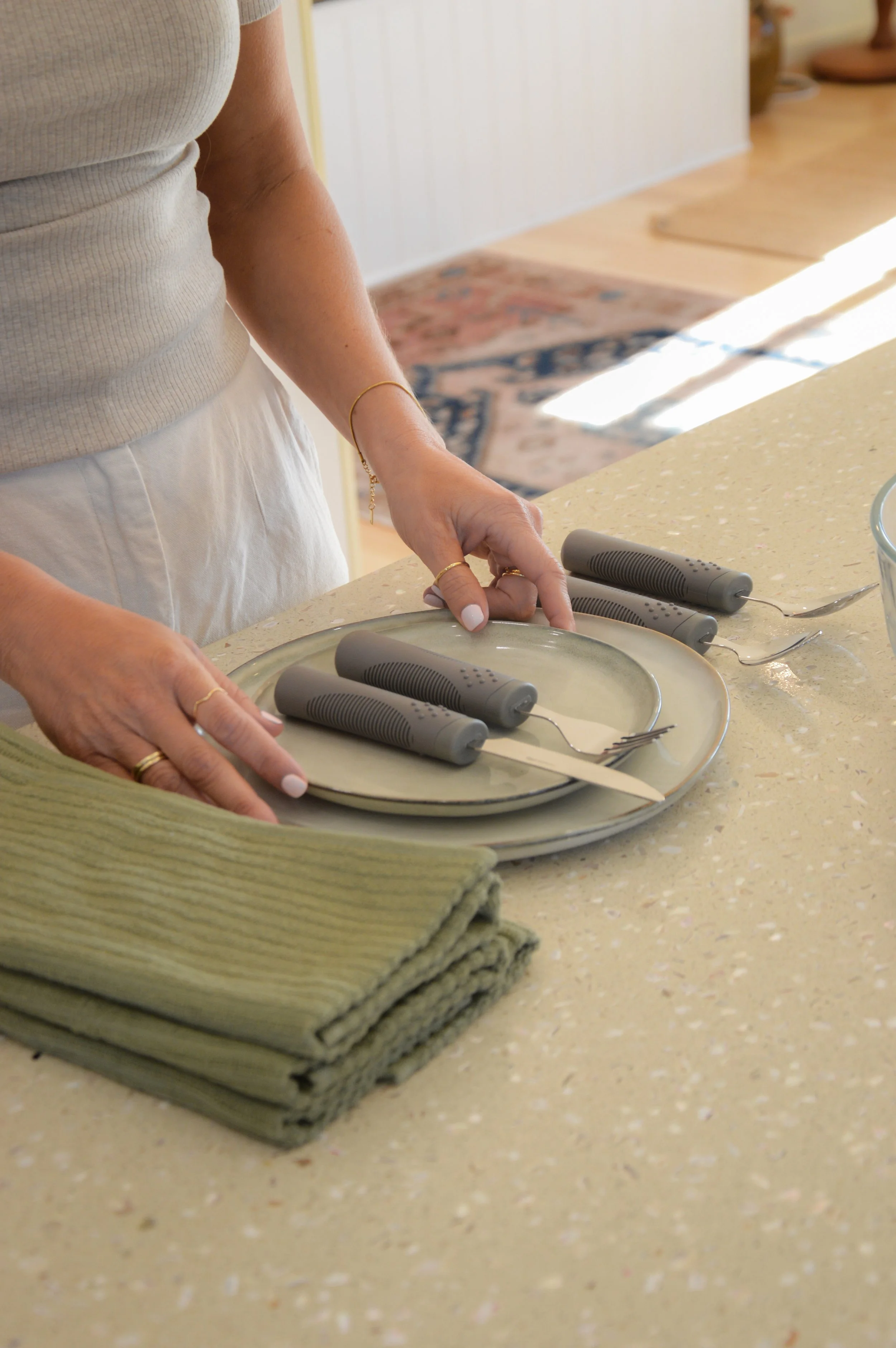 Woman setting a table with plates, knife and fork.