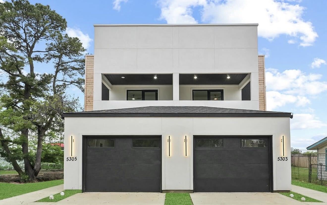 Exterior view of The Colonial model by Echelon Development & Design, featuring a contemporary white facade, dark double garage doors, upper balcony, and integrated accent lighting.