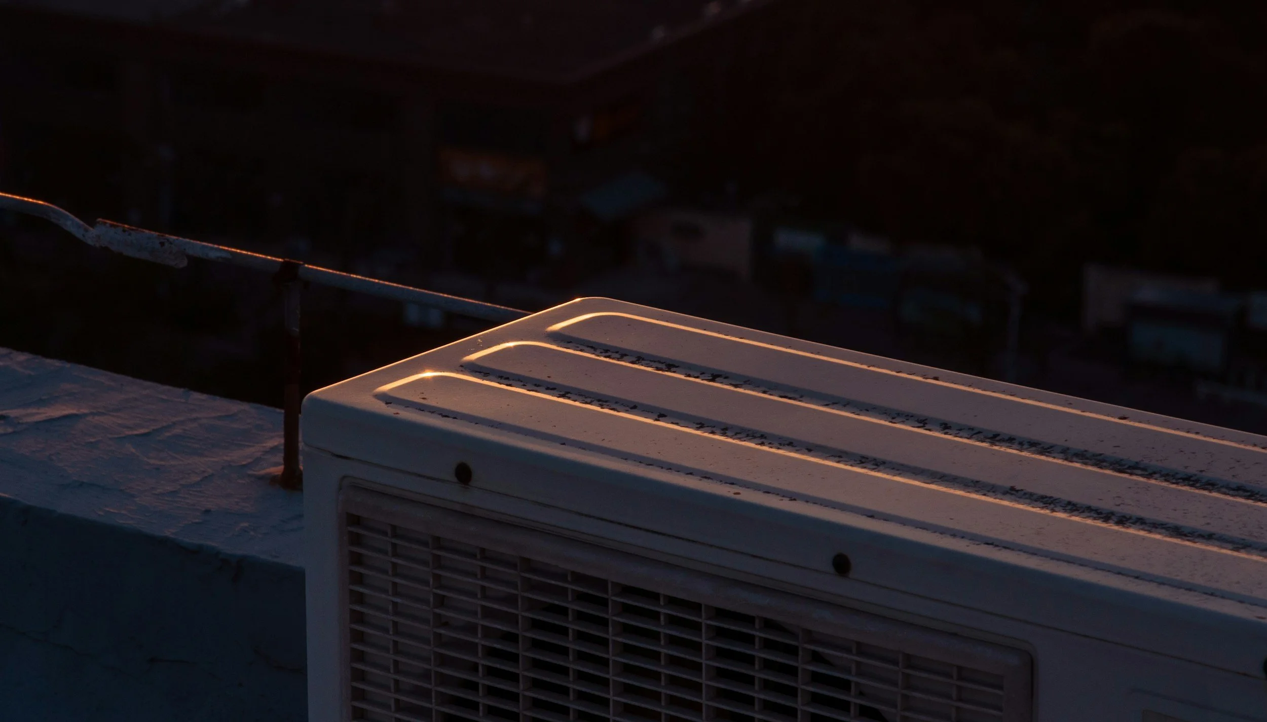 Snow-covered rooftop air conditioning unit at dusk