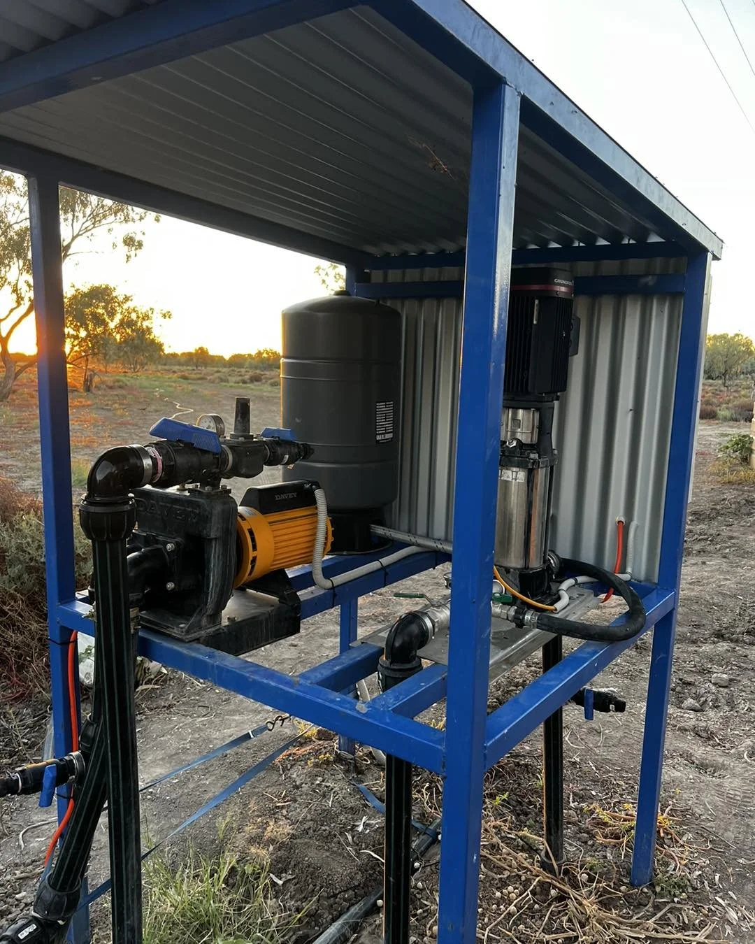 Outdoor agricultural water filtration and pumping system housed in a blue metal shelter