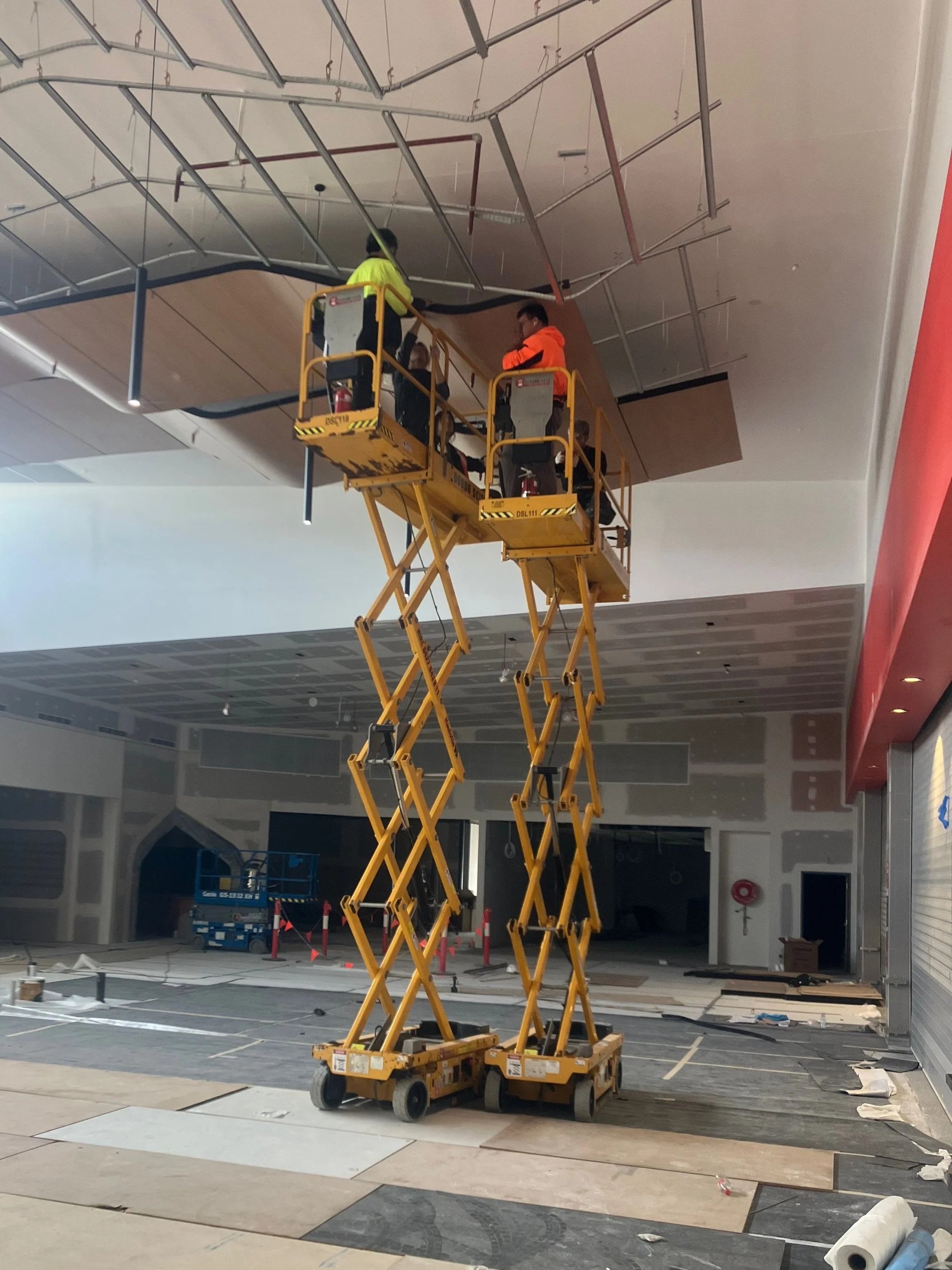 Two men working on interior roofing with Opti-8 Scissor Lifts