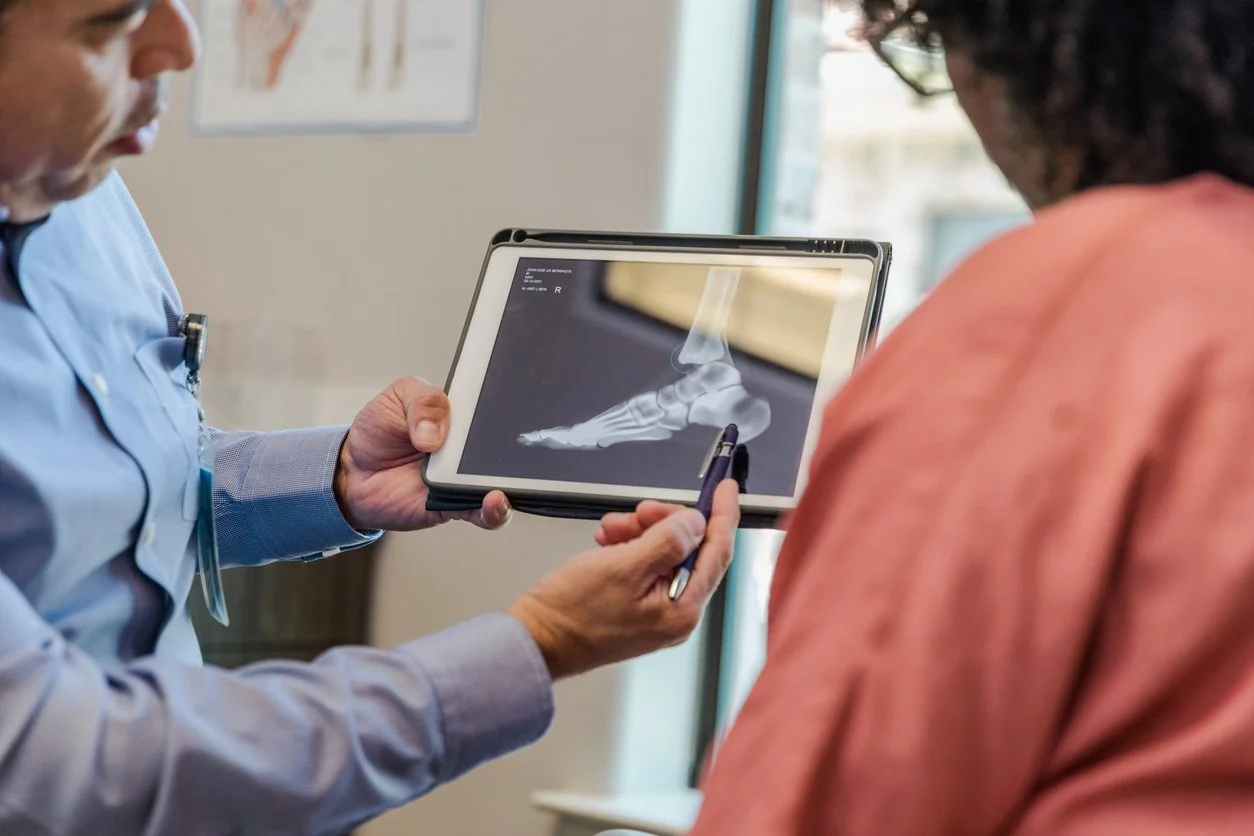 Doctor showing an X-ray of a foot and ankle to a patient with a tablet