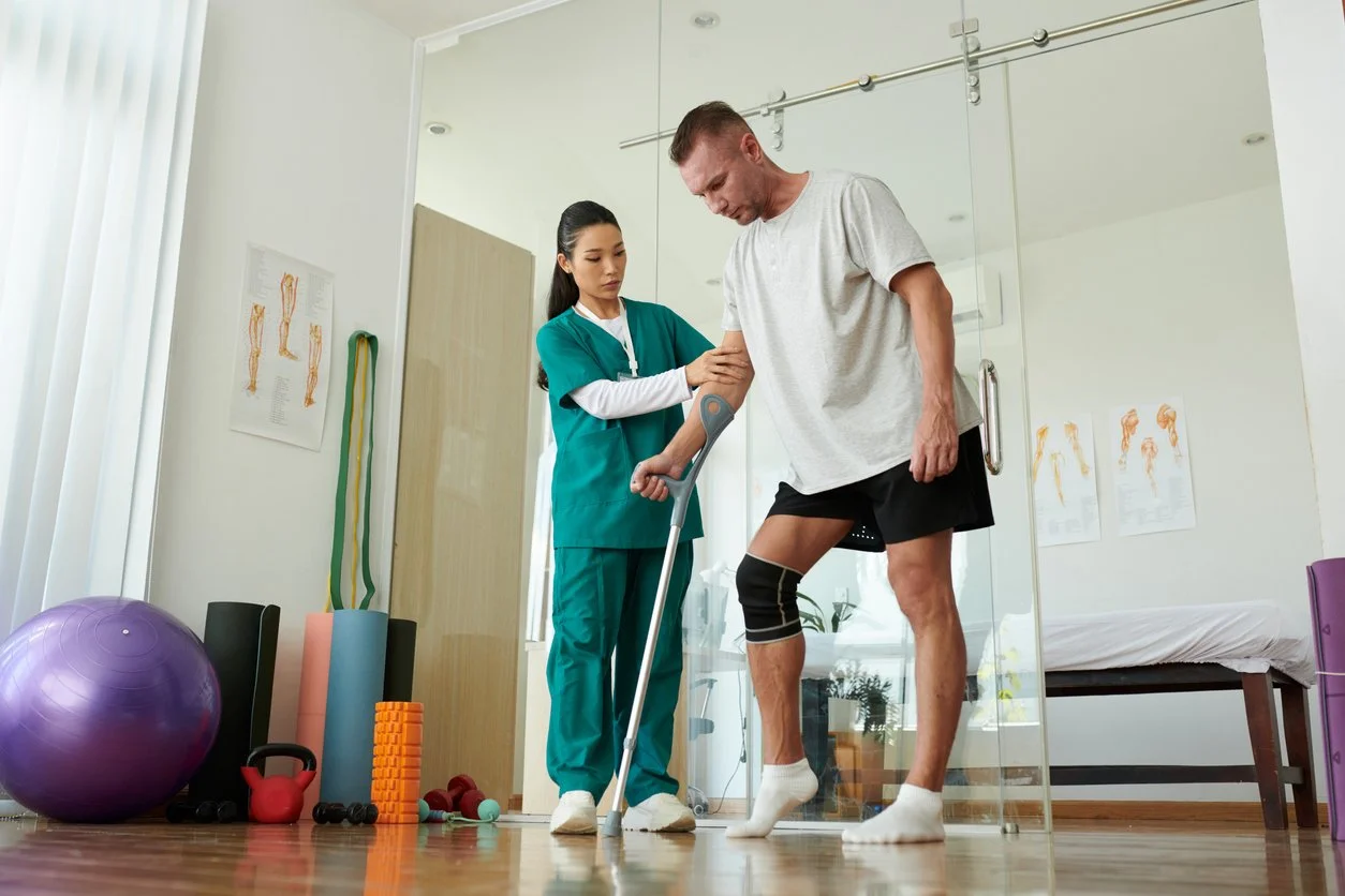 Physical therapist assisting a man with a knee injury during a physiotherapy session in a clinic.