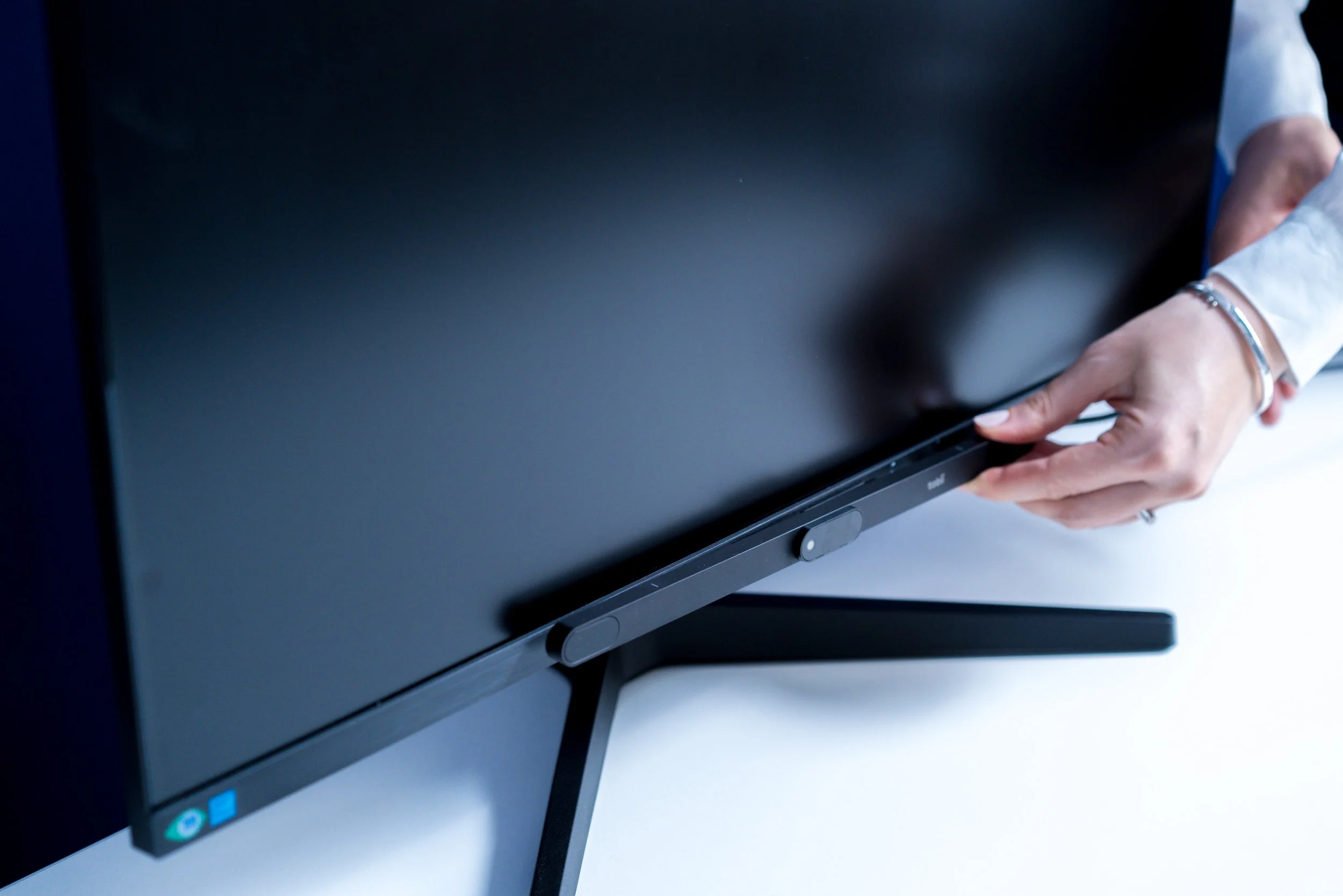 Close-up of a person's hand touching a computer screen in an office setting.