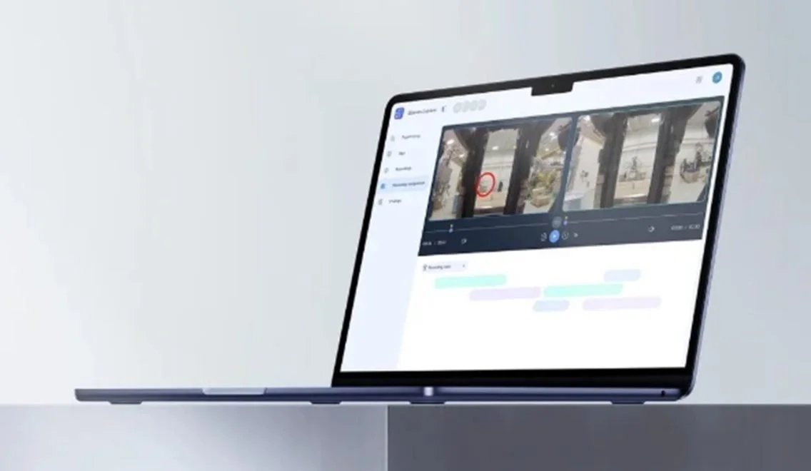 A laptop displaying a video editing or transcript editing software on a light-colored desk and wall.
