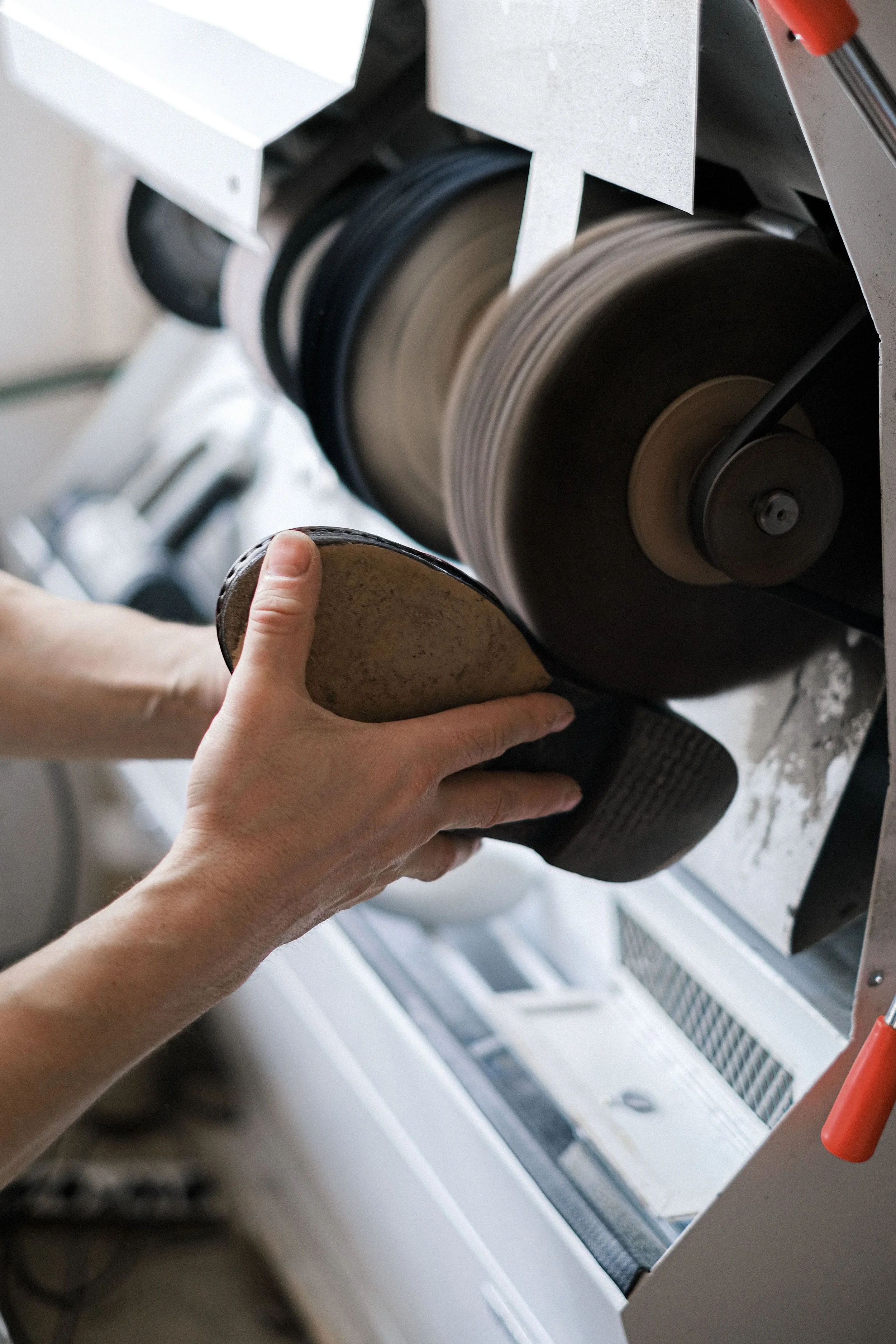 Iemand vaart een schijf op een transportband in een industrieel machine. De machine heeft metalen onderdelen en wordt mogelijk gebruikt voor het snijden of op maat maken van materialen.