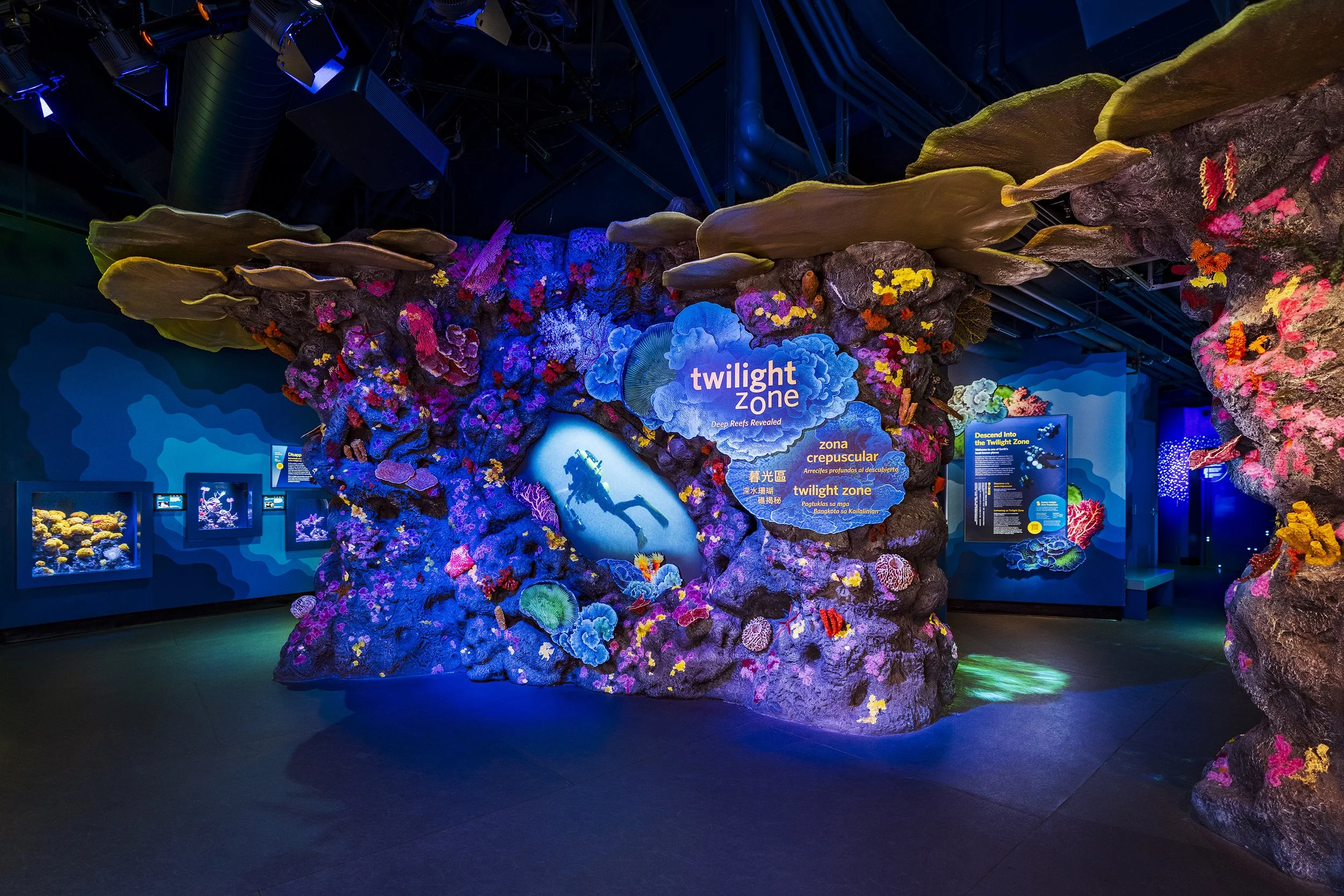 The entry wall combines sculpted rockwork, touchable models, projection, graphics, and dynamic lighting to create a dramatic context for Twilight Zone stories. 