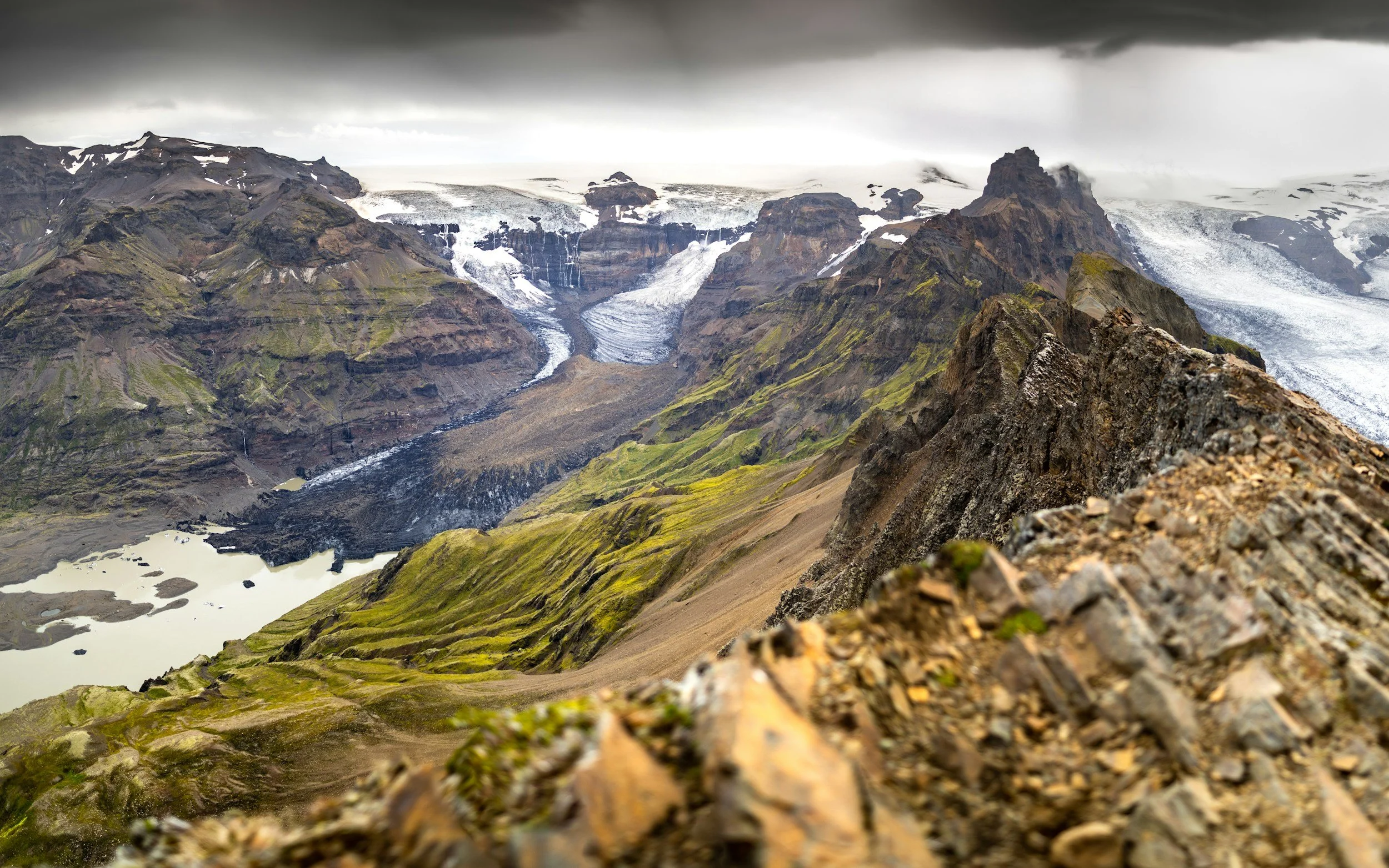 mountain landscape with glaciers, rocky terrain, and dark cloudy sky