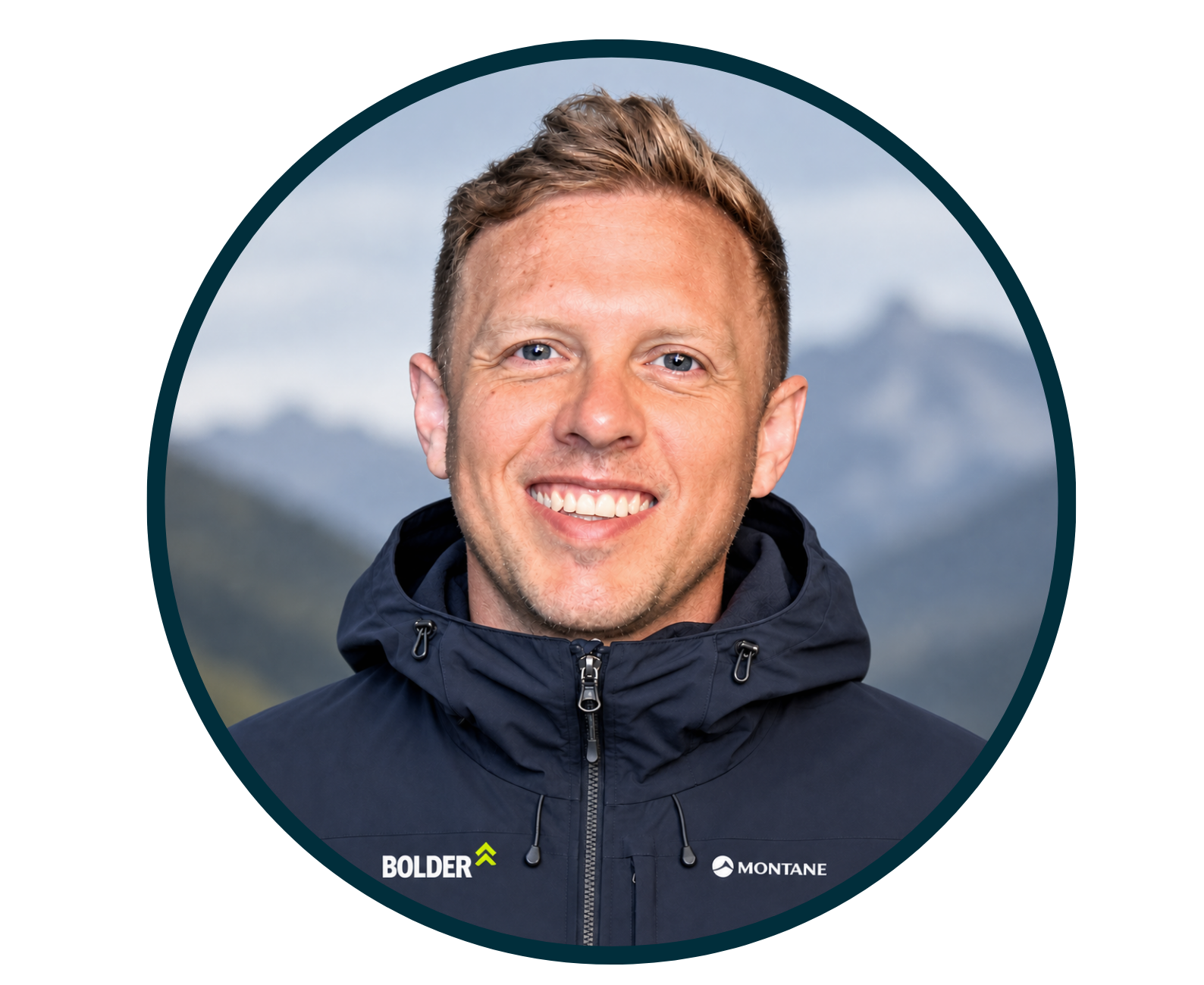 Smiling man in a black outdoor jacket with mountain background.