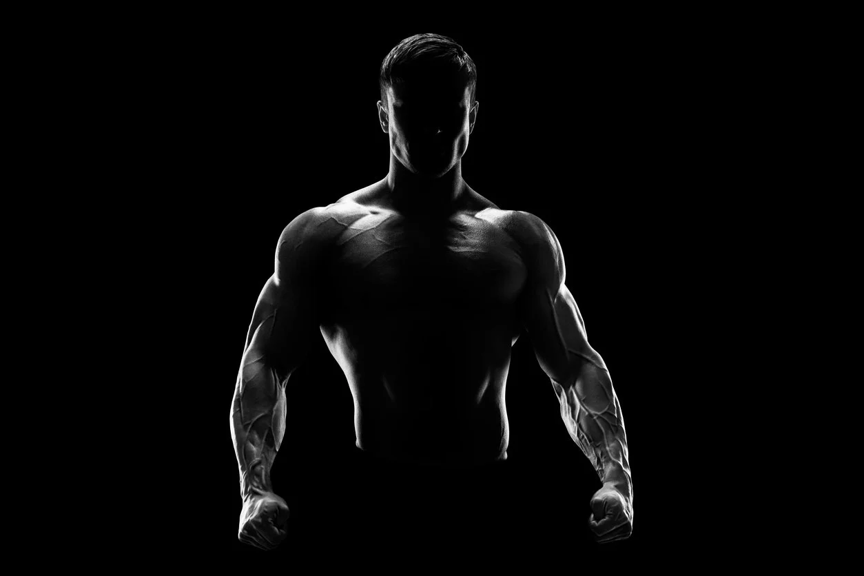 Silhouette of a muscular man representing Live Superhuman Experience with clenched fists against a black background.