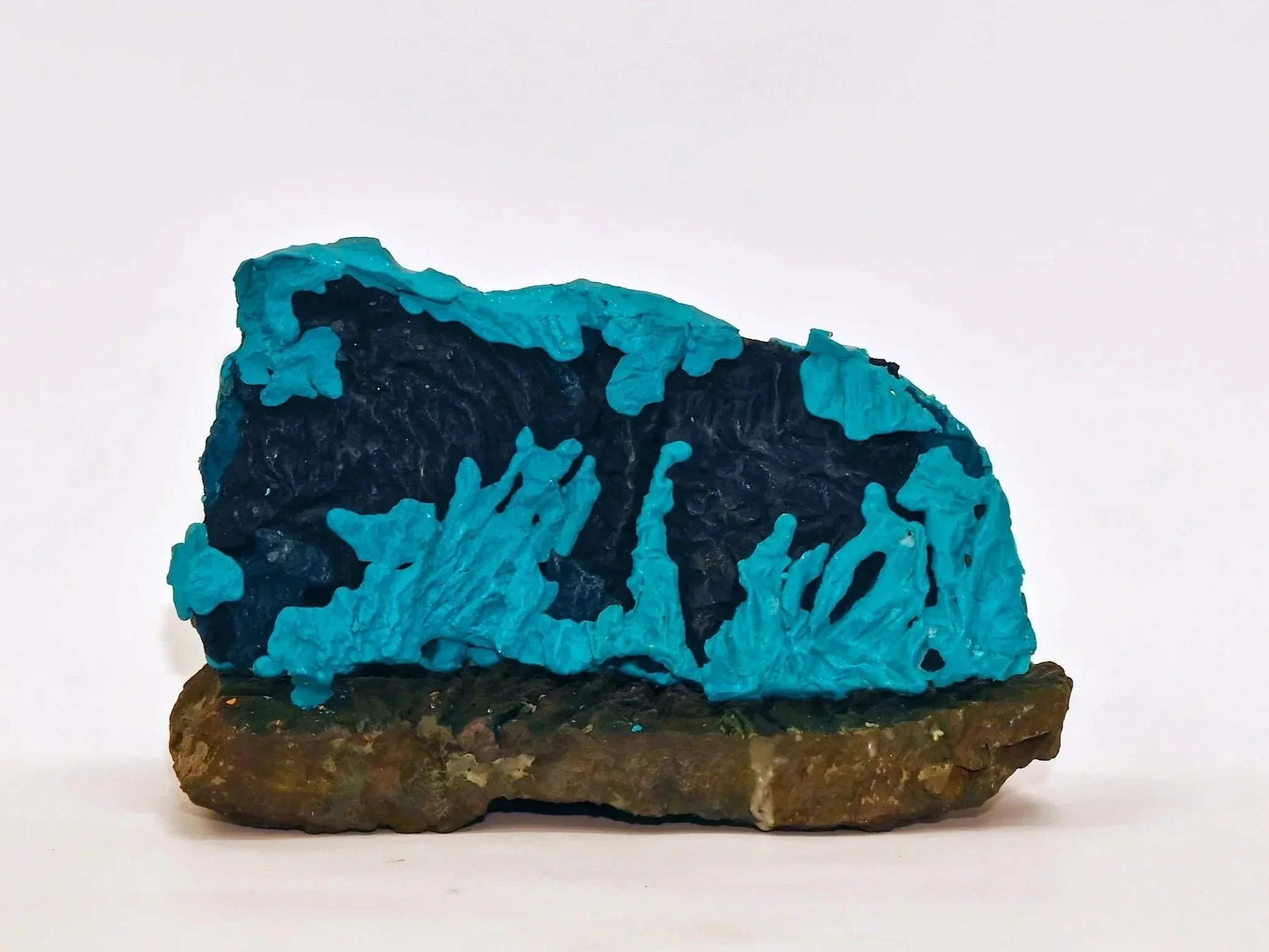 A blue mineral or crystal formation on a brown rocky base.