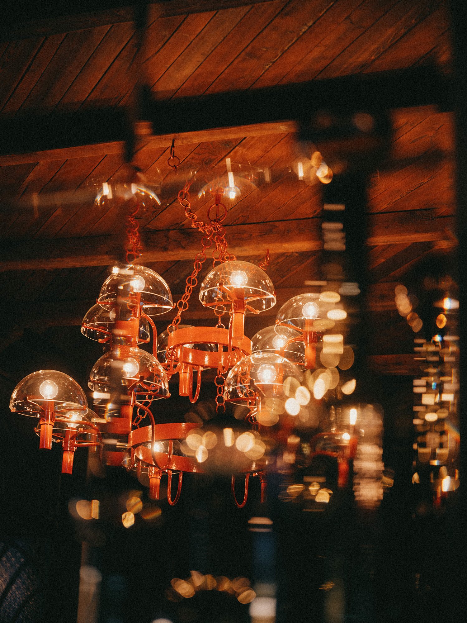 Lustre moderne aux lumières chaleureuses, dont les globes en verre sont suspendus à un plafond en bois.
