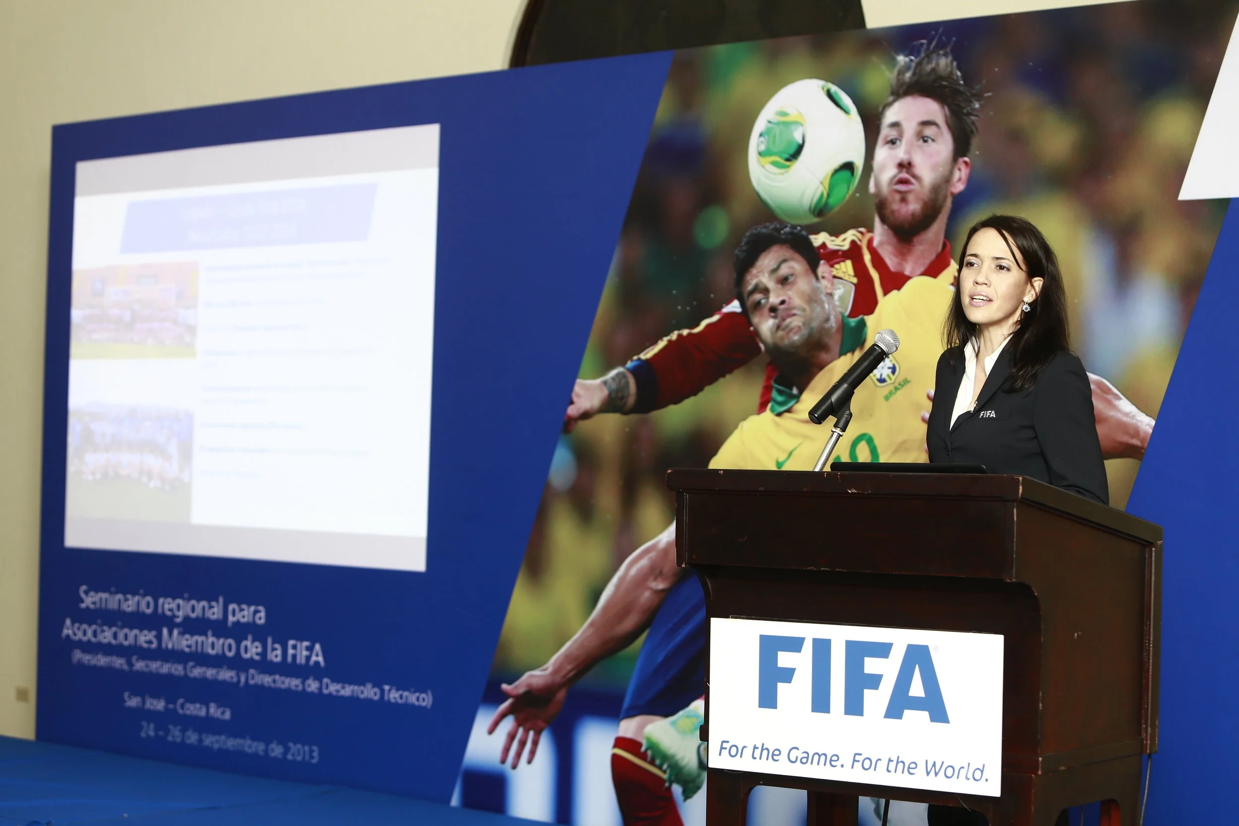 Banner advertising a regional seminar for member associations of FIFA, featuring an image of a soccer player in yellow jersey heading a ball, woman speaker at podium, and FIFA logo.