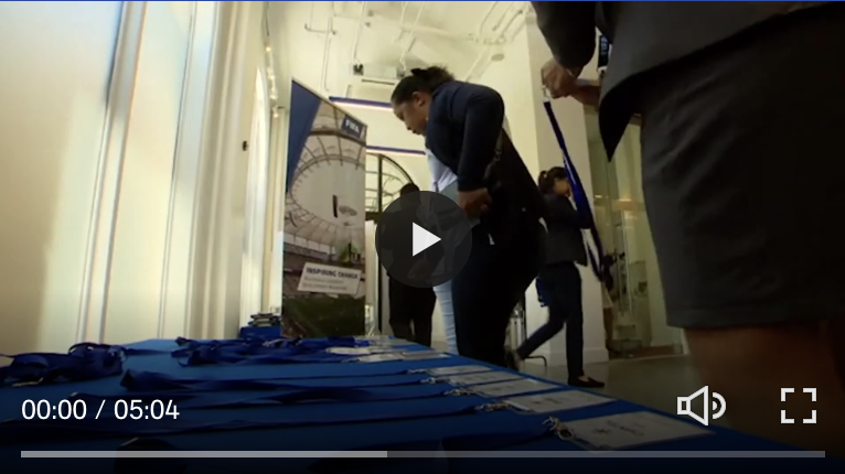 People attending an event, examining a table with blue lanyards and name tags in a conference room.