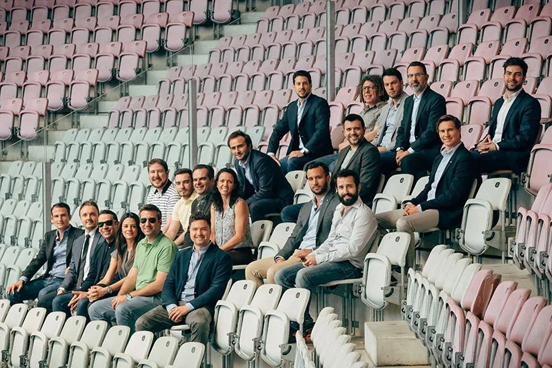 Group of professional people sitting in stadium seats, posing for a photo.