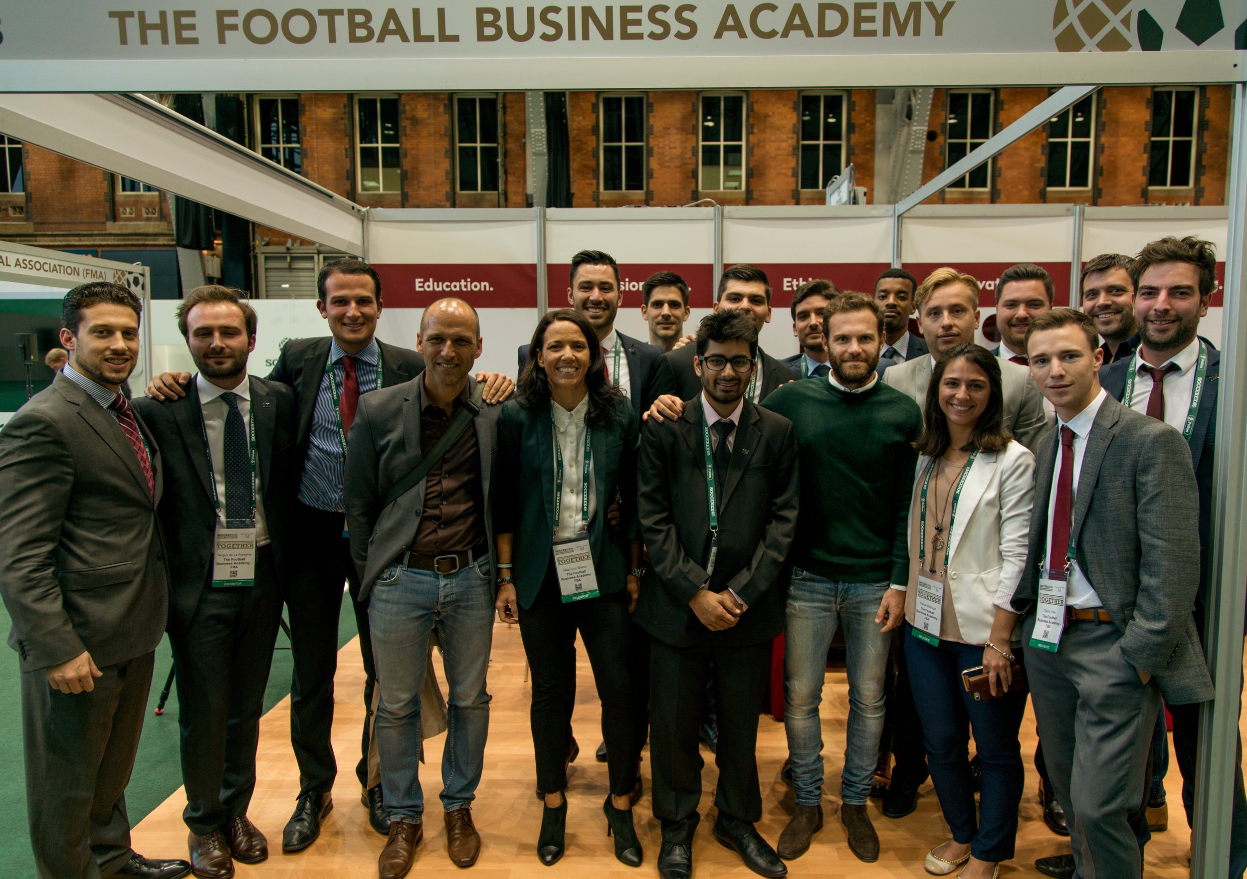 Group of diverse professionals smiling at an event with a banner reading 