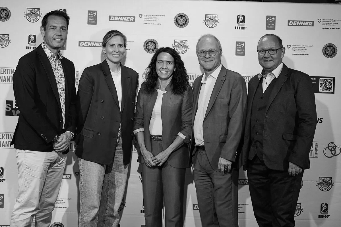 Group of six people standing in front of a backdrop with various logos, including Red Bull, Swiss, Denner, and others, at a formal event.