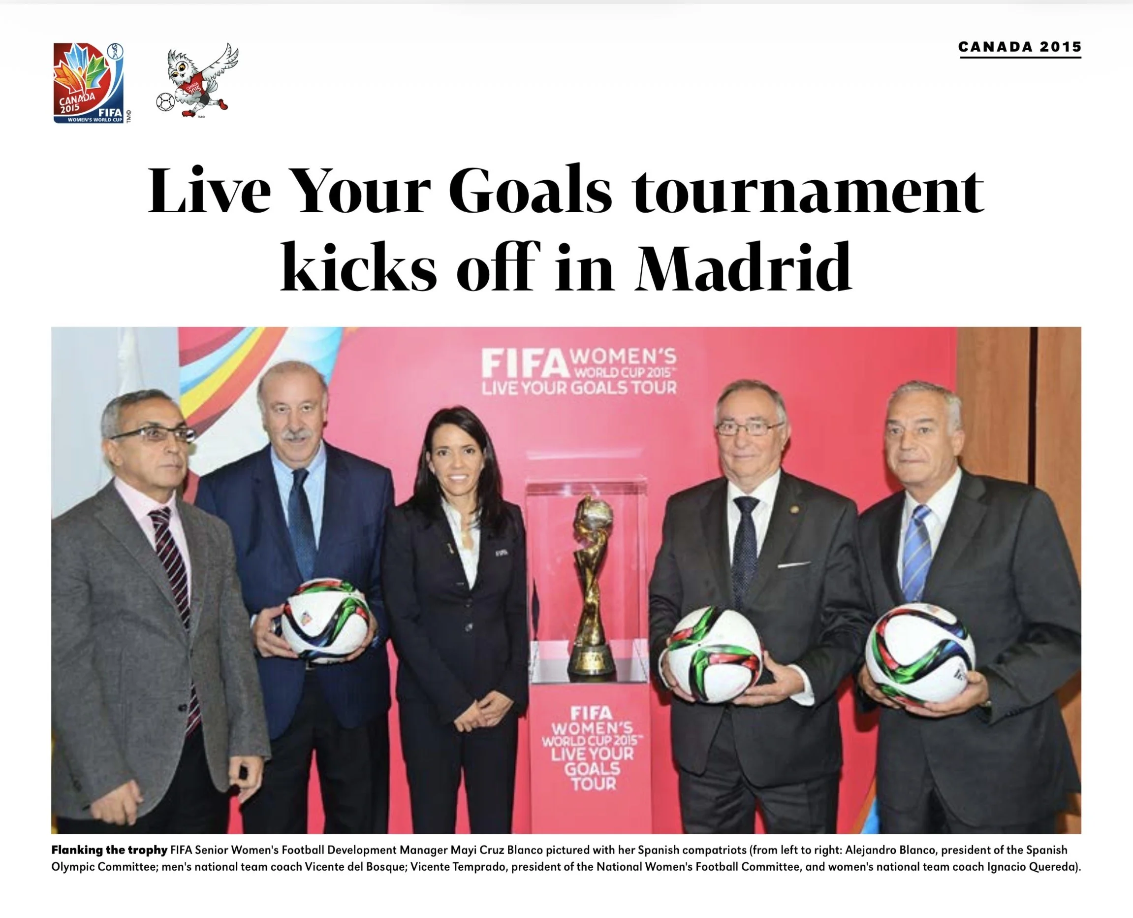 Group of six individuals, five men and one woman, standing behind a display of FIFA Women's World Cup 2015 trophies and soccer balls, at an event promoting the tournament in Madrid.