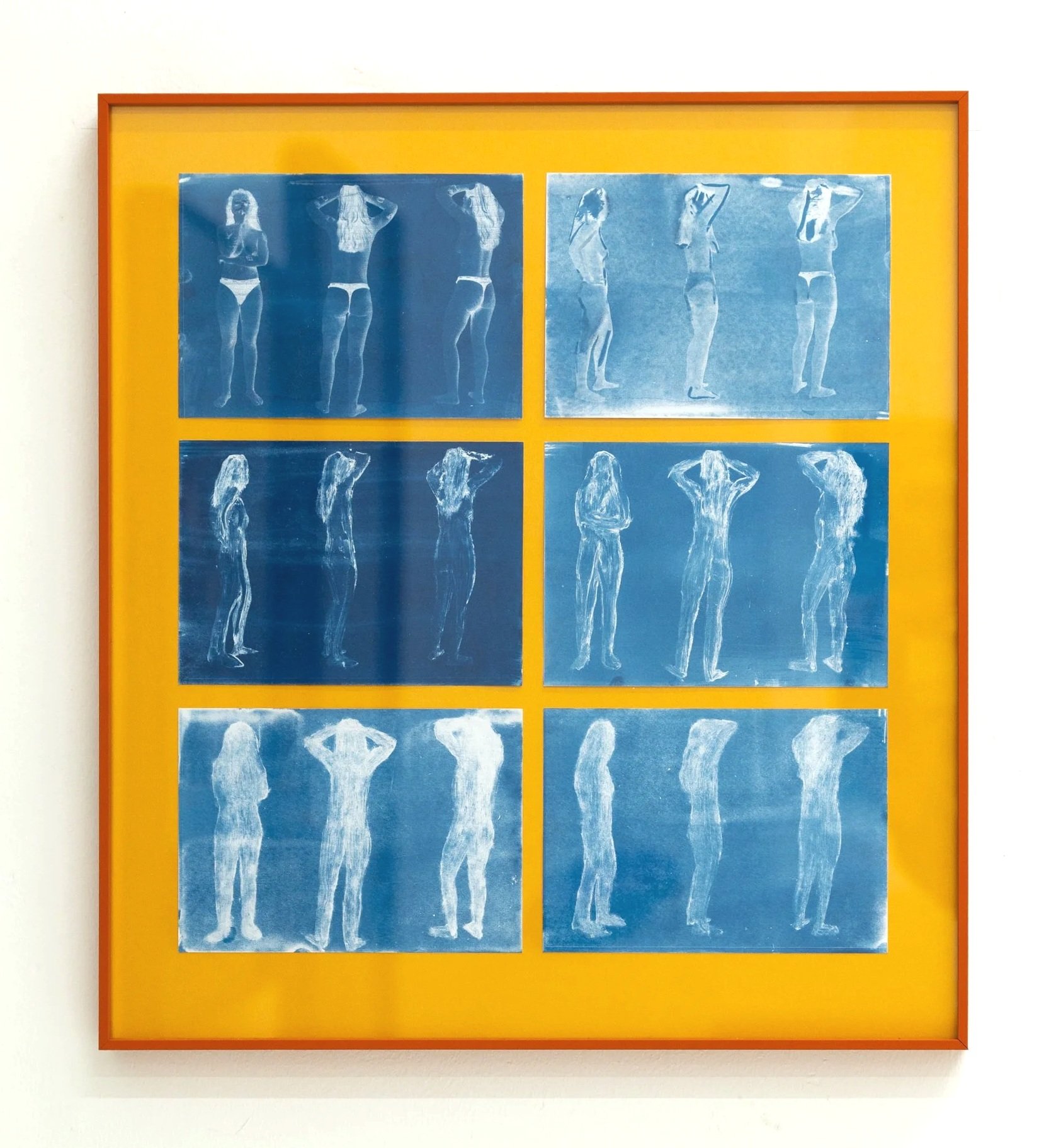 A framed artwork featuring a series of blue monochrome silhouette photographs of a woman in various poses, arranged in four panels on a yellow background, mounted on a white wall.