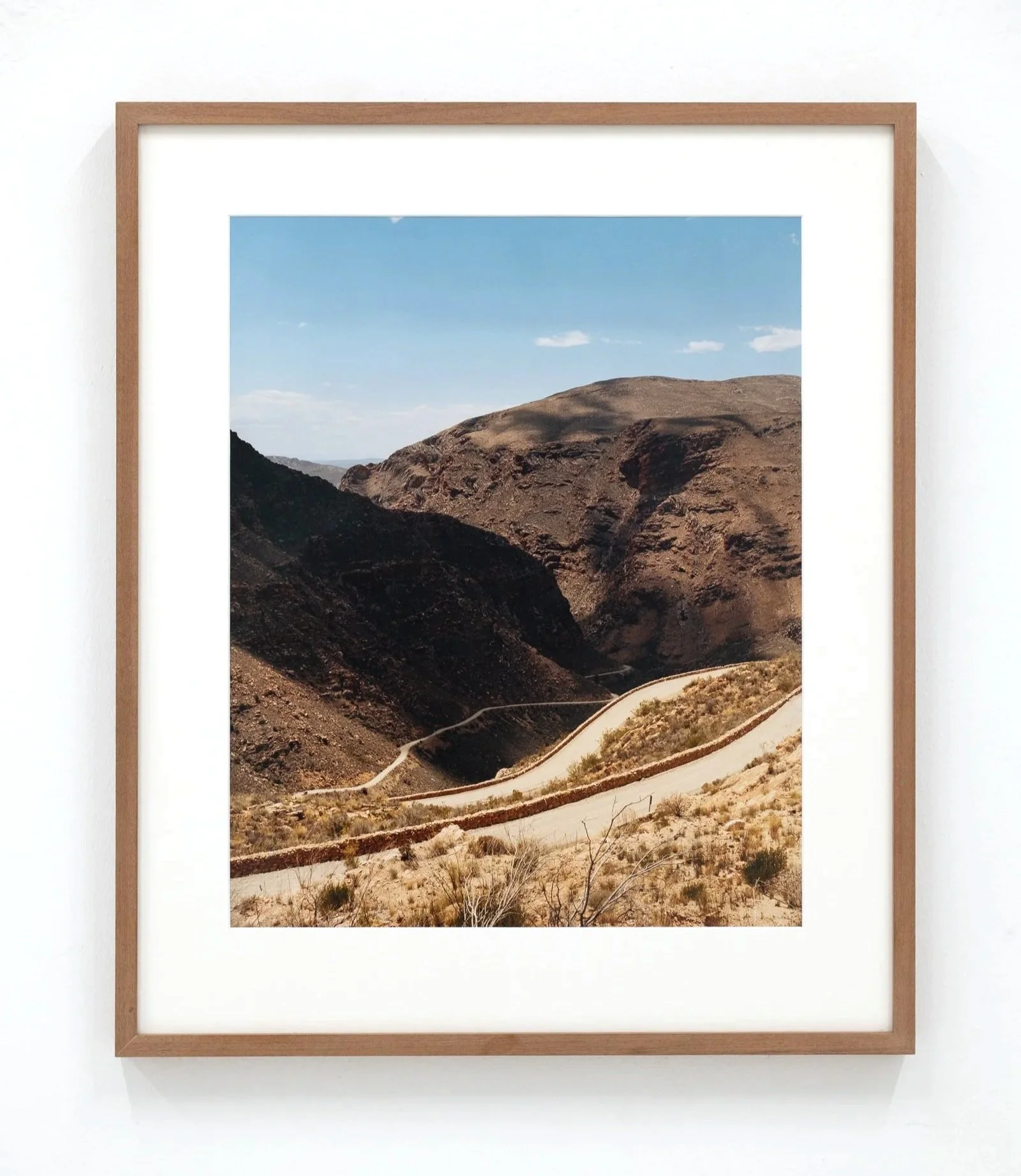 Photograph of a mountainous desert landscape with dry, rocky terrain and a winding dirt road.