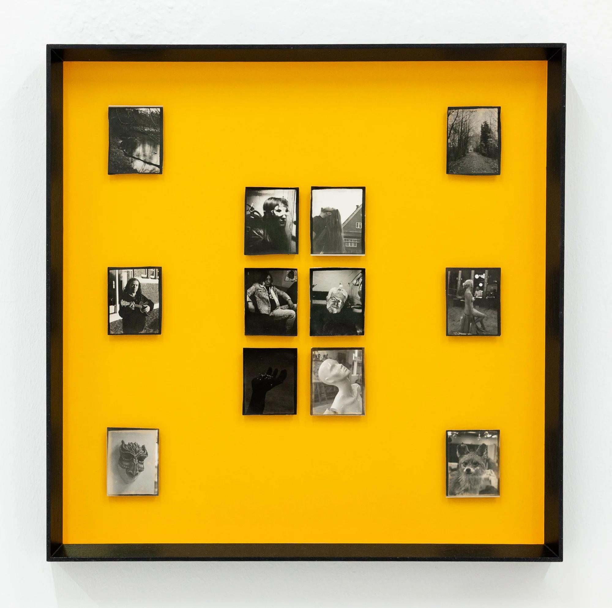 A black photo frame with a yellow background displaying multiple black and white photographs of people and scenery.