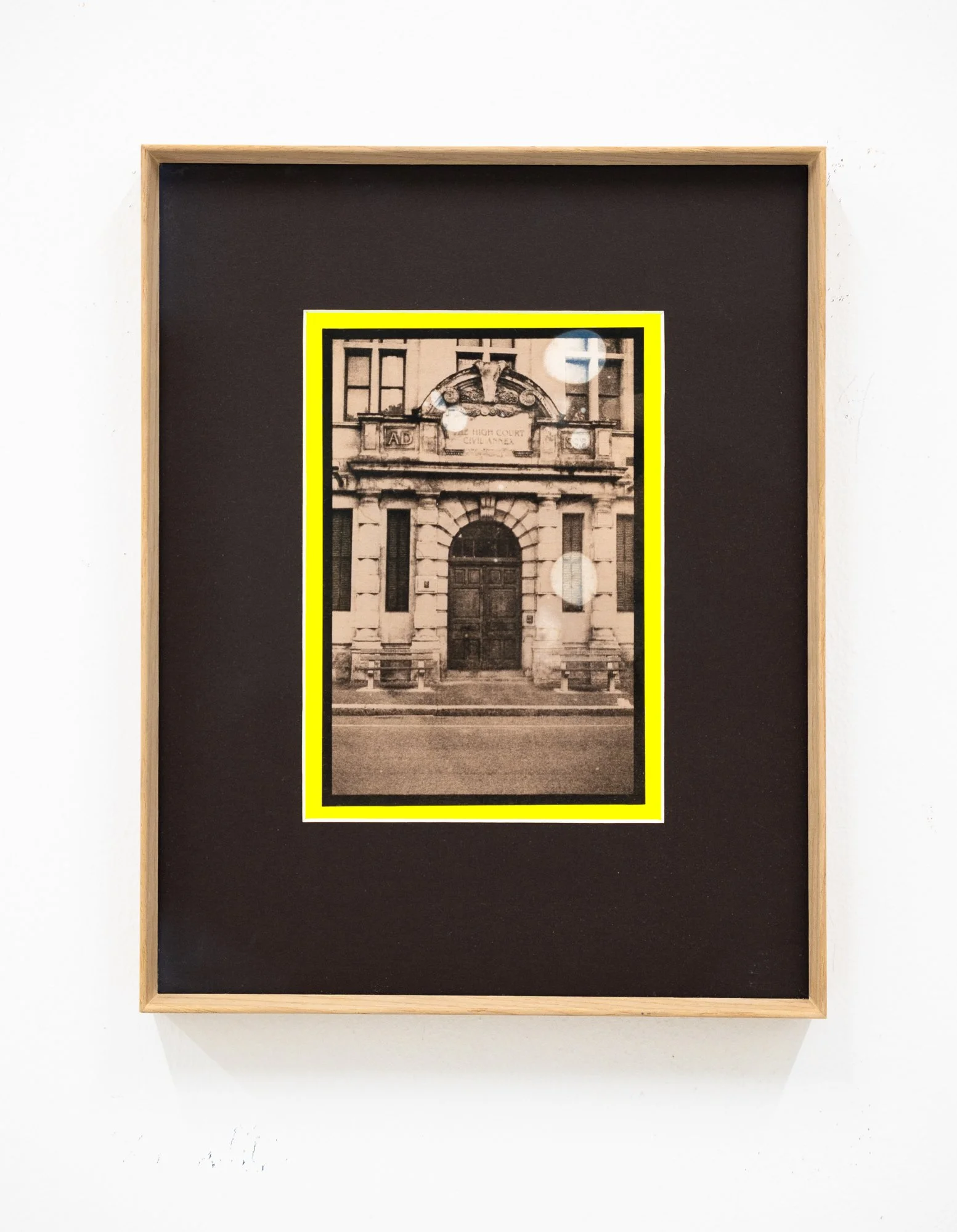 Black and white photograph of a historic building with a decorative arched entrance inside a yellow border on brown background.