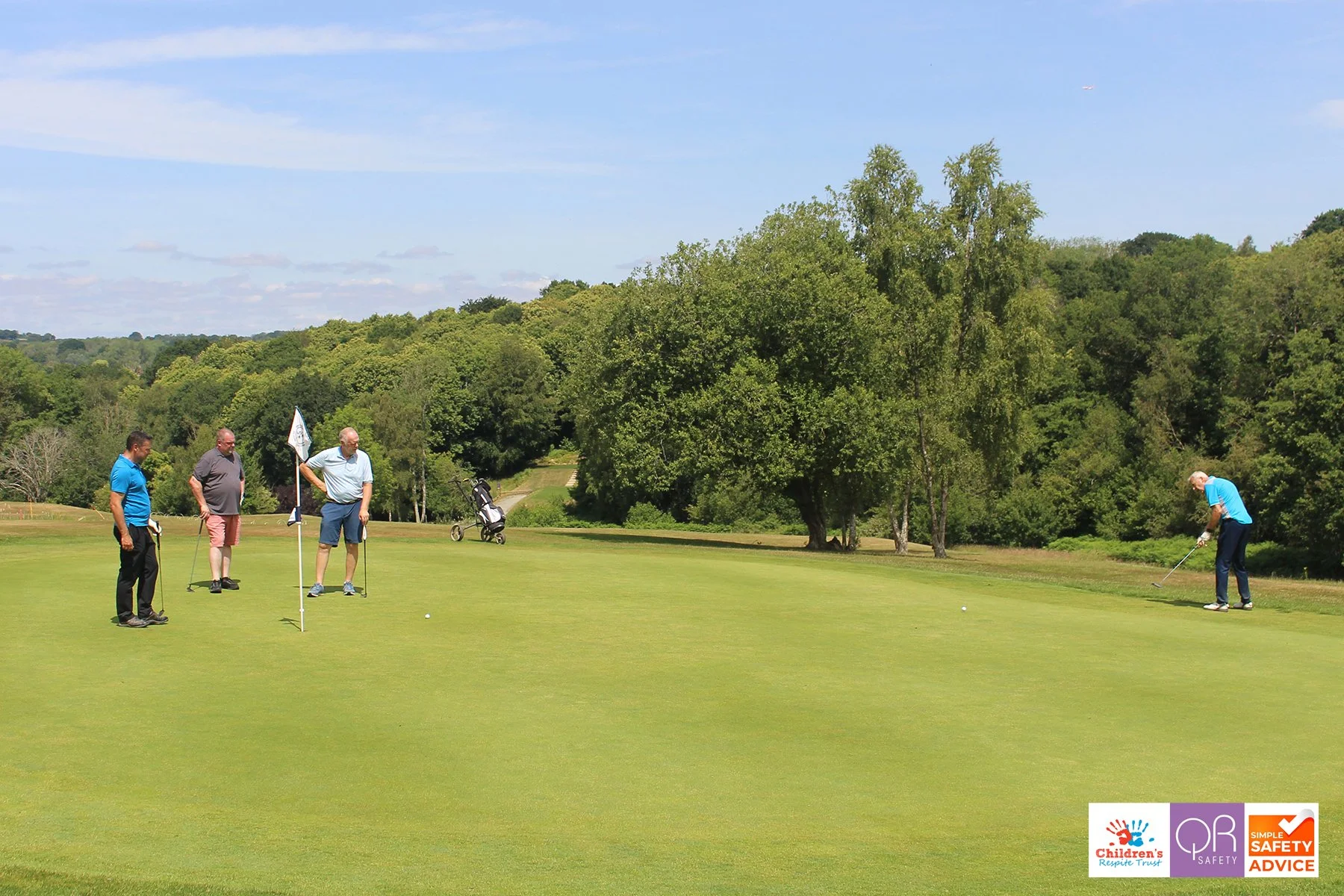 Four men on a golf course preparing to putt, with a golf cart and trees in the background, and logos for Children's Response Trust, OP Safety, and Safety Advice in the bottom right corner.