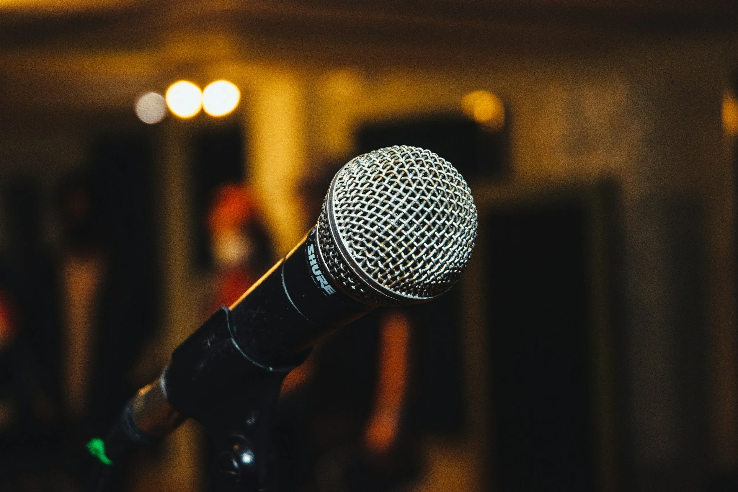 A microphone on a stand in a dimly lit room, likely set up for a performance or speech.